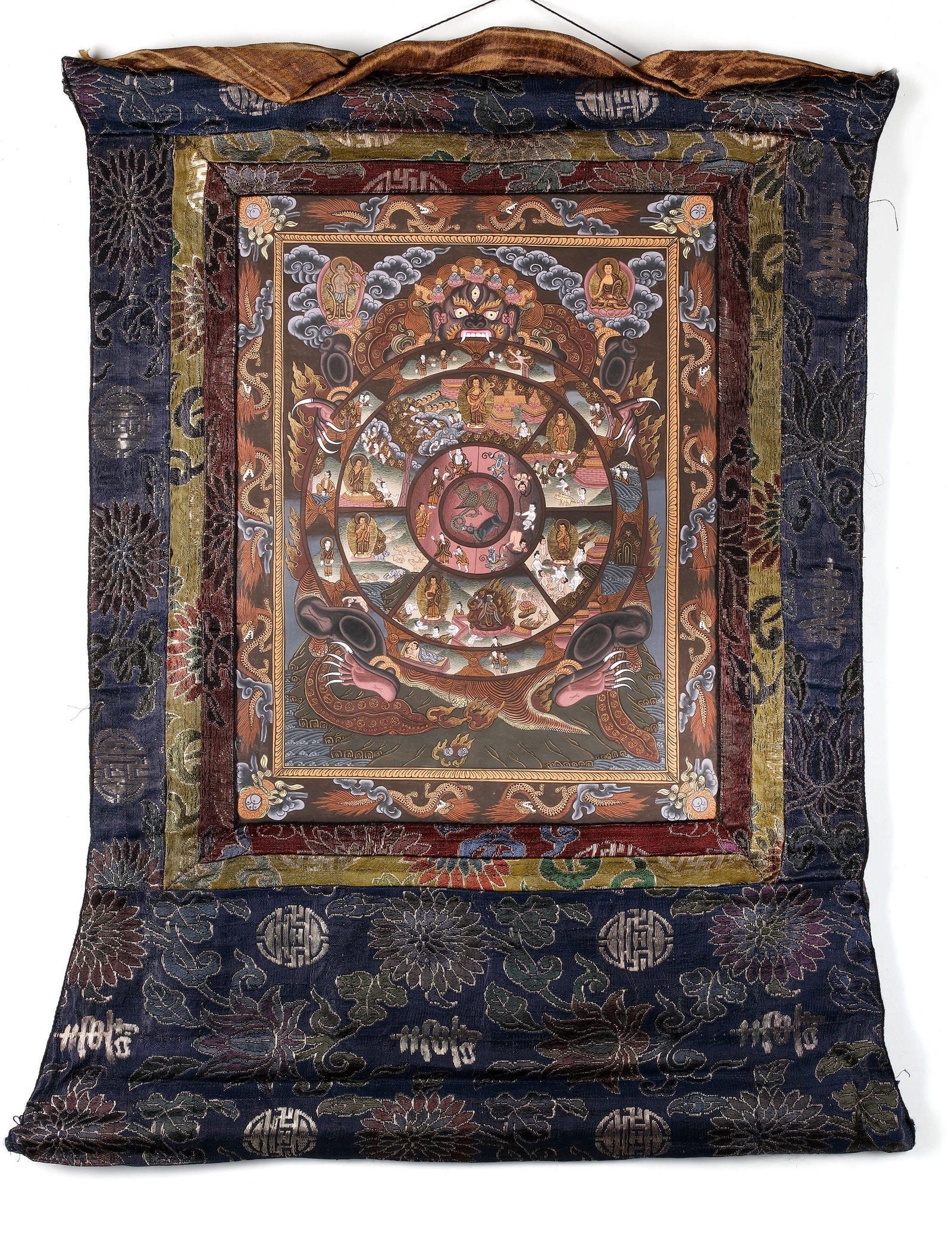 A WHEEL OF LIFE THANGKA, TIBET, 20TH CENTURY: A richly detailed Tibetan thangka depicting the Buddhist Wheel of Life (Bhavachakra), symbolizing the cycle of existence, karma, and rebirth. The composition features sacred figures, symbolic scenes, 