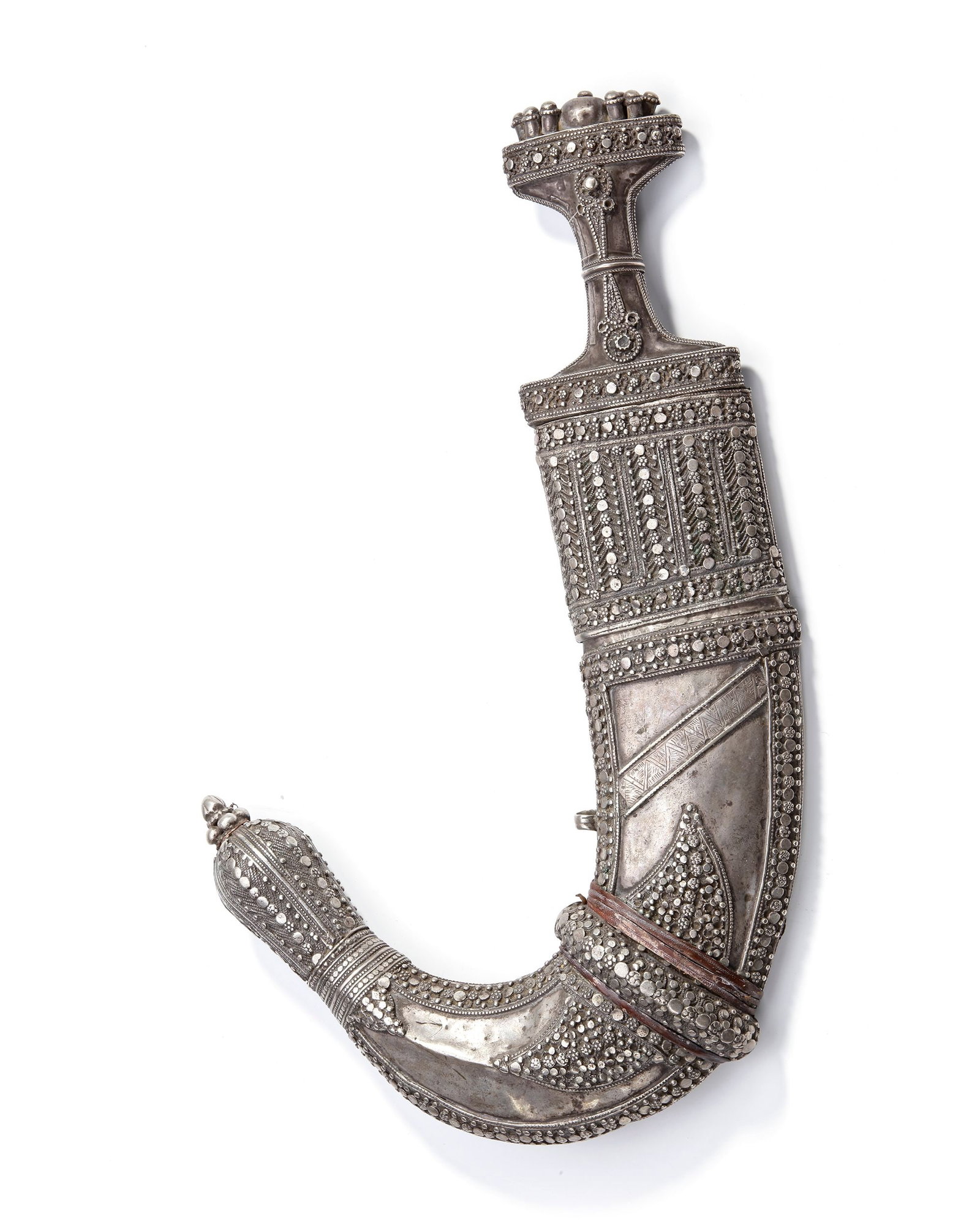 A SILVER DAGGER, SAUDI ARABIA, 19TH CENTURY: Richly decorated with intricate granulation, filigree, and raised silver studs. The hilt is adorned with bold ornamental designs, while the curved scabbard features elaborate geometric and floral patt