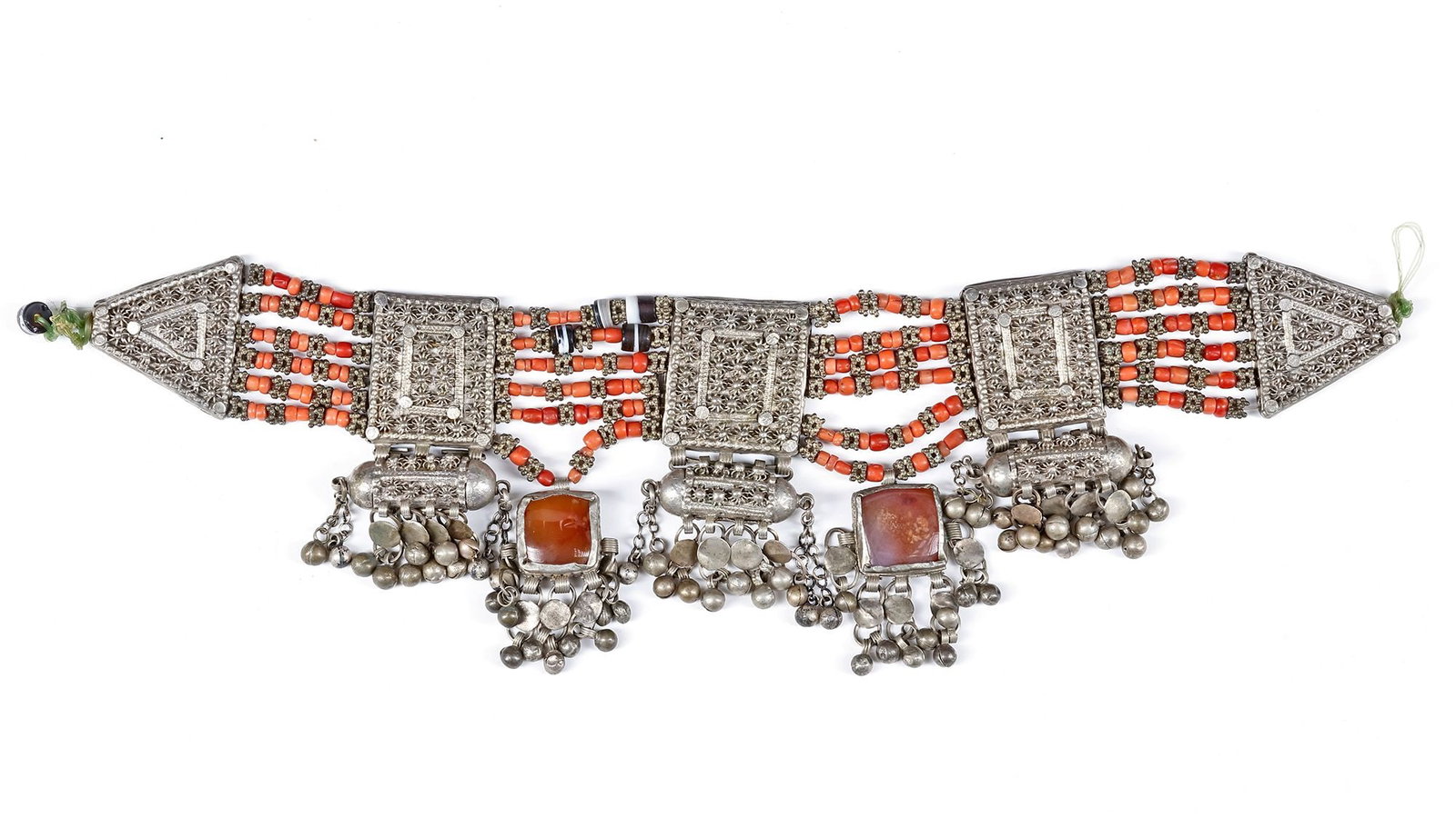 AN ISLAMIC SILVER NECKLACE, YEMEN, 19TH CENTURY: Richly decorated with intricate filigree panels, coral bead strands, and inset carnelian stones. The piece features hanging silver dangles and amulet-like elements. 40 by 10 cm. 377 gr. THE DR. SAAD A