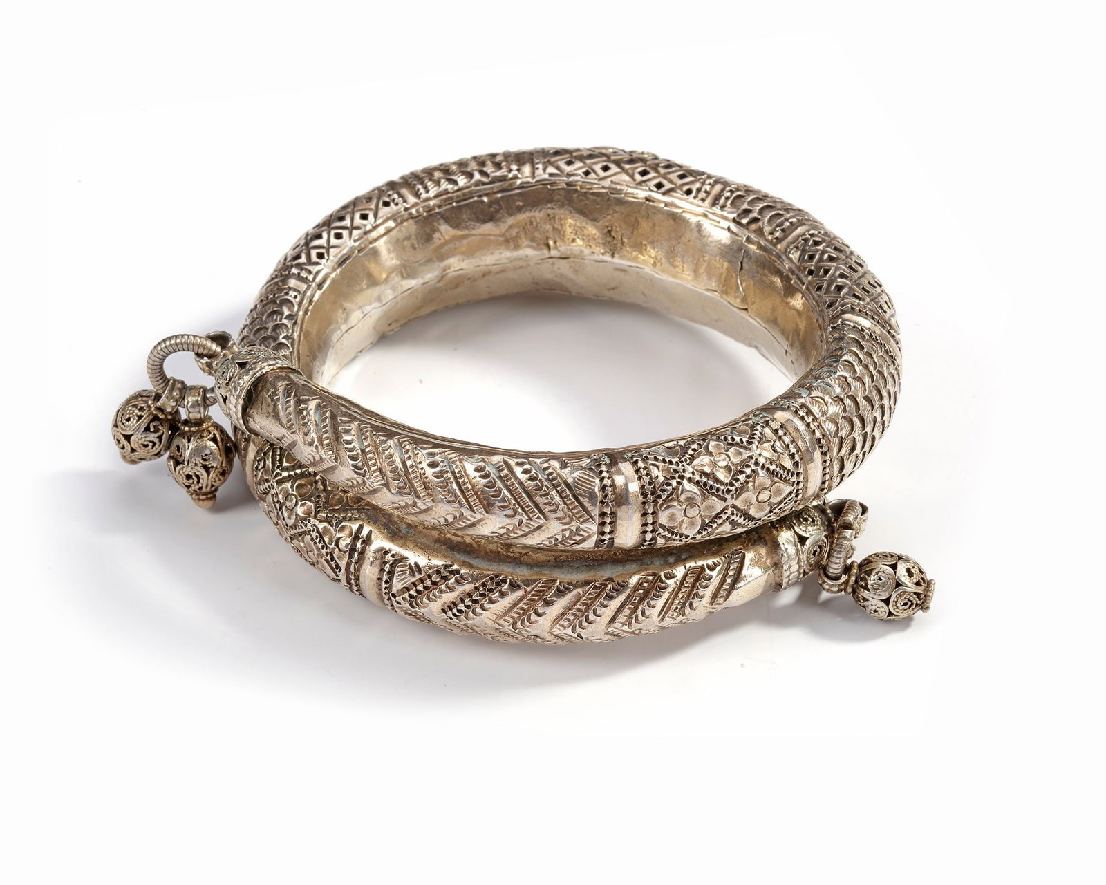 A SILVER BRACELET, EGYPT, 19TH CENTURY: Richly decorated with engraved geometric and floral patterns. The piece features bold repouss?© designs, intricate filigree details, and hanging silver spheres. 10 cm. 103 gr. THE DR. SAAD AL-JADIR C