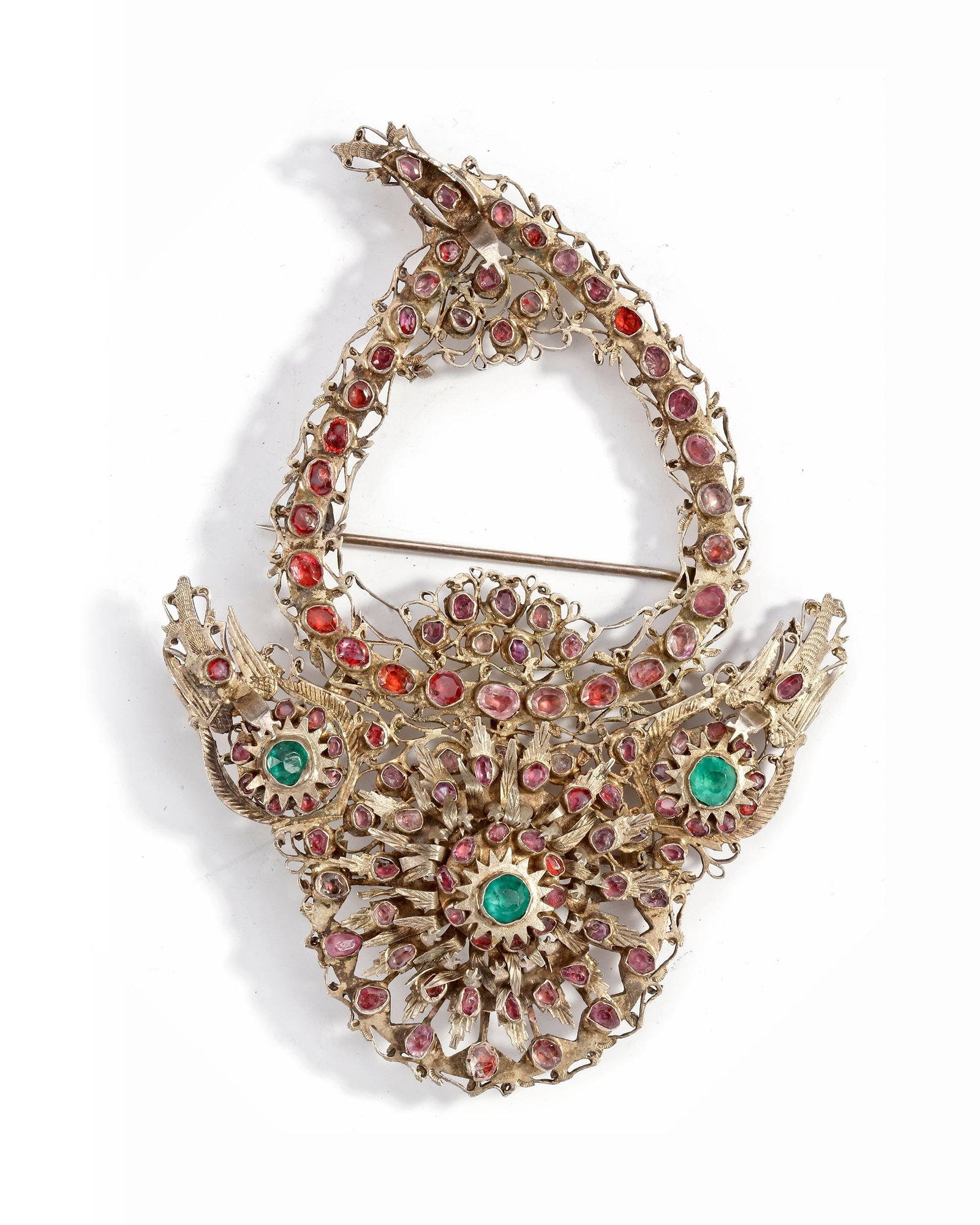 AN ALGERIAN BELT BUCKLE,19TH CENTURY: Ornate Algerian silver belt buckle set with red stones and emerald cabochons, featuring a crescent and floral motif in intricate openwork design. A striking piece of traditional ceremonial jewelry. 11