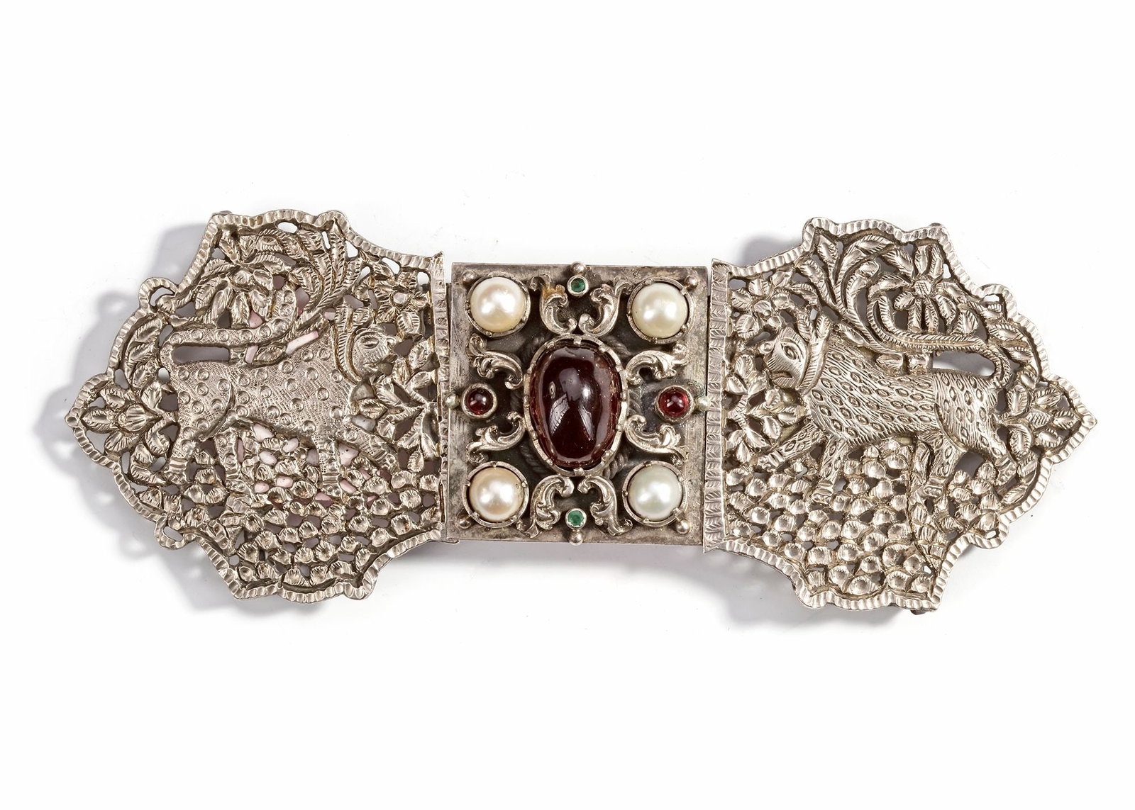 A SILVER BELT BUCKLE, INDIA, 20TH CENTURY: Finely crafted with pierced floral and animal motifs depicting leopards among foliage. The central section is richly adorned with pearls, garnets, and green stones. 14 by 6 cm. 87 gr. THE DR. SAAD AL-