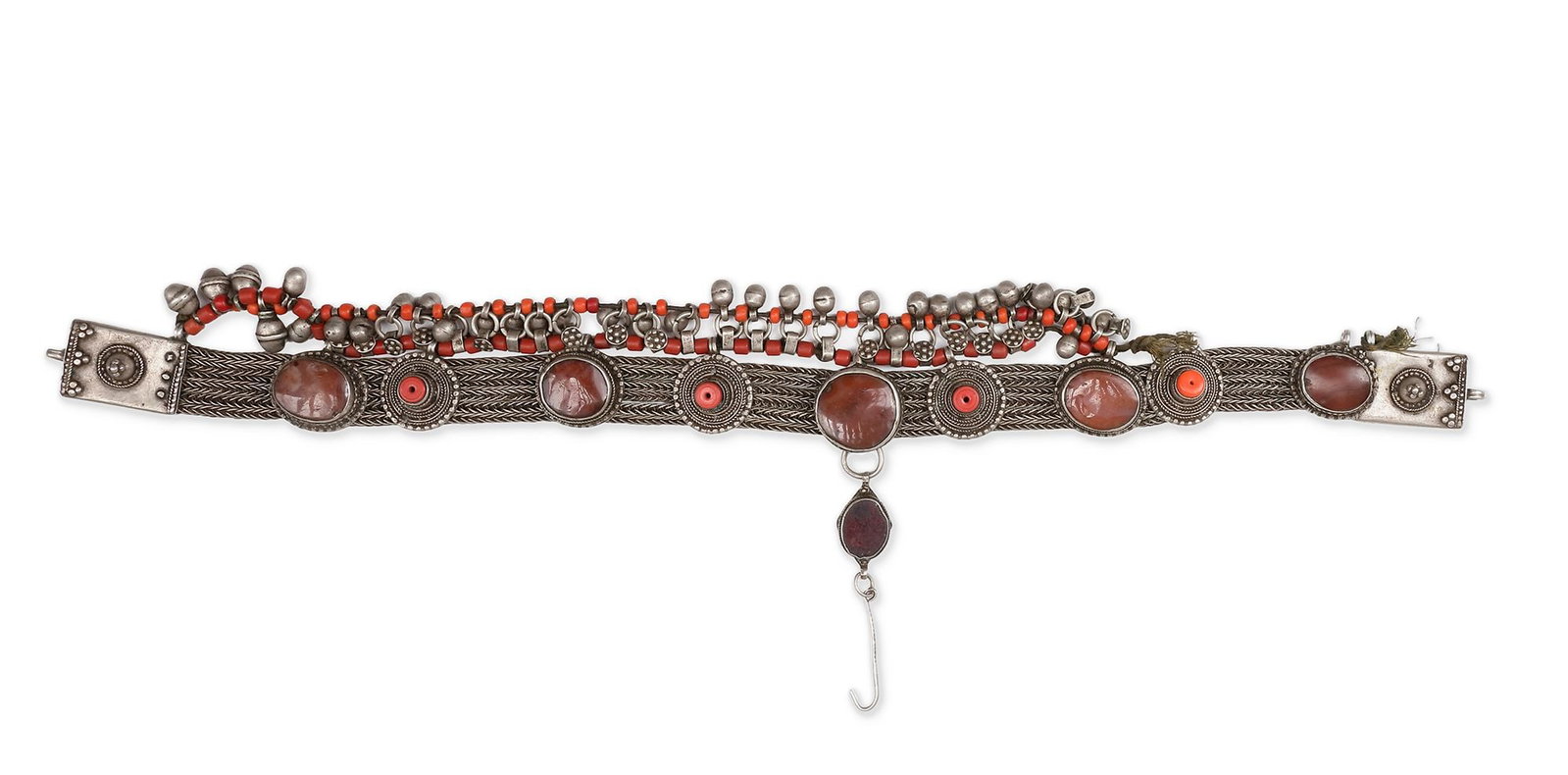 A SILVER BRACELET, MOROCCO, 19TH CENTURY: An ornate Moroccan bracelet crafted in silver, adorned with large cabochon stones and red coral beads. Detailed filigree and engraved patterns 42 by 8 cm. 216 gr. THE DR. SAAD AL-JADIR COLLECTION