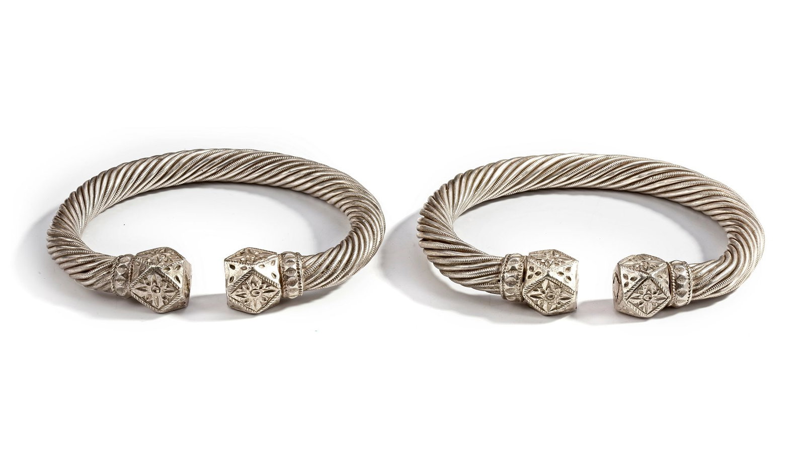 A PAIR OF SILVER BRACELETS, OMAN, 19TH CENTURY: A pair of heavy Omani silver bracelets featuring twisted rope designs with finely engraved geometric hexagonal terminals. 12 cm. 677 gr. THE DR. SAAD AL-JADIR COLLECTION