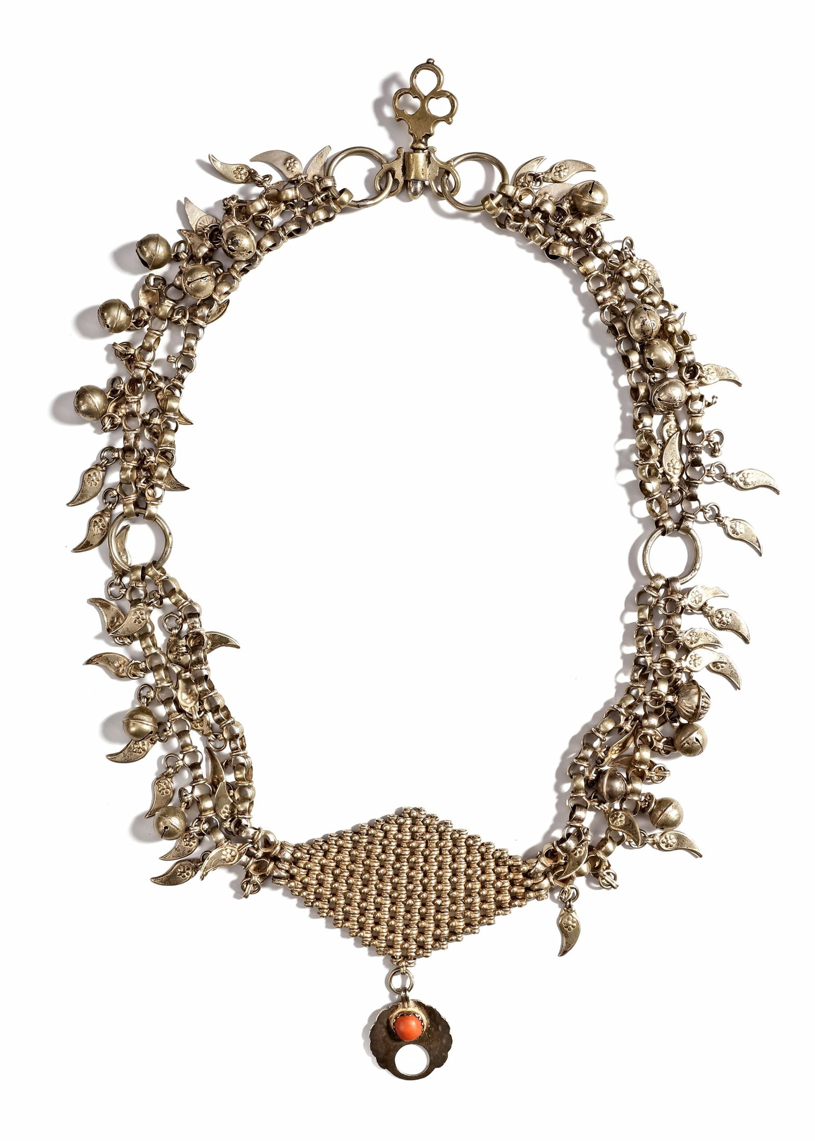 A SILVER NECKLACE, IRAQ, 20TH CENTURY: RIchly decorated with dangling bells, leaf-shaped pendants, and a central woven panel. Finished with a coral-set pendant. ca. 80 cm. 483 gr. THE DR. SAAD AL-JADIR COLLECTION