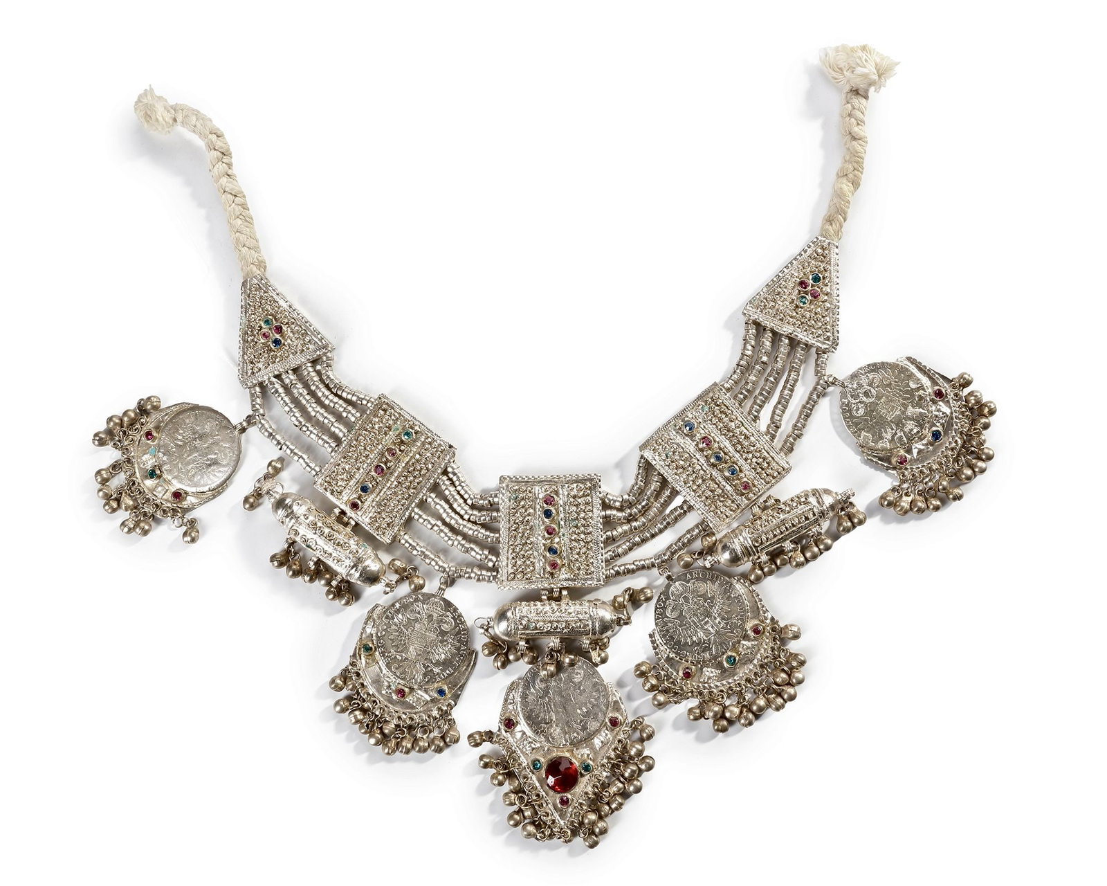 A SILVER NECKLACE, SAUDI ARABIA, EARLY 20TH CENTURY: Featuring elaborate filigree panels, suspended amulet-like pendants, and mounted silver coins adorned with colorful glass inlays. 37 by 17 cm. 518 gr. THE DR. SAAD AL-JADIR COLLECTION