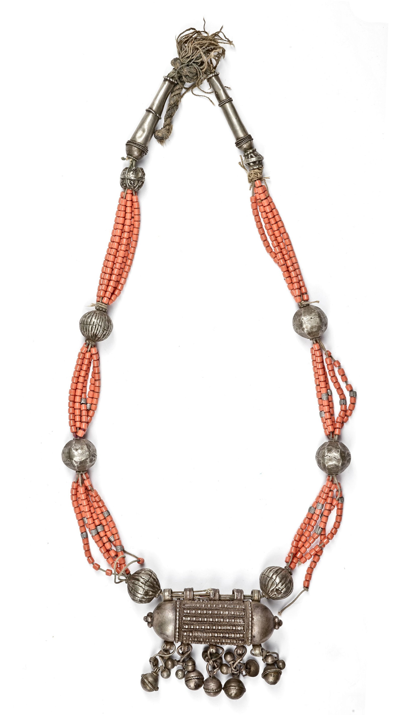 A SILVER NECKLACE, YEMEN, 19TH CENTURY: A traditional Yemeni necklace featuring multiple strands of red coral beads, interspaced with hammered silver spheres. The centerpiece is an ornate silver amulet box (hirz), richly decorated with intr