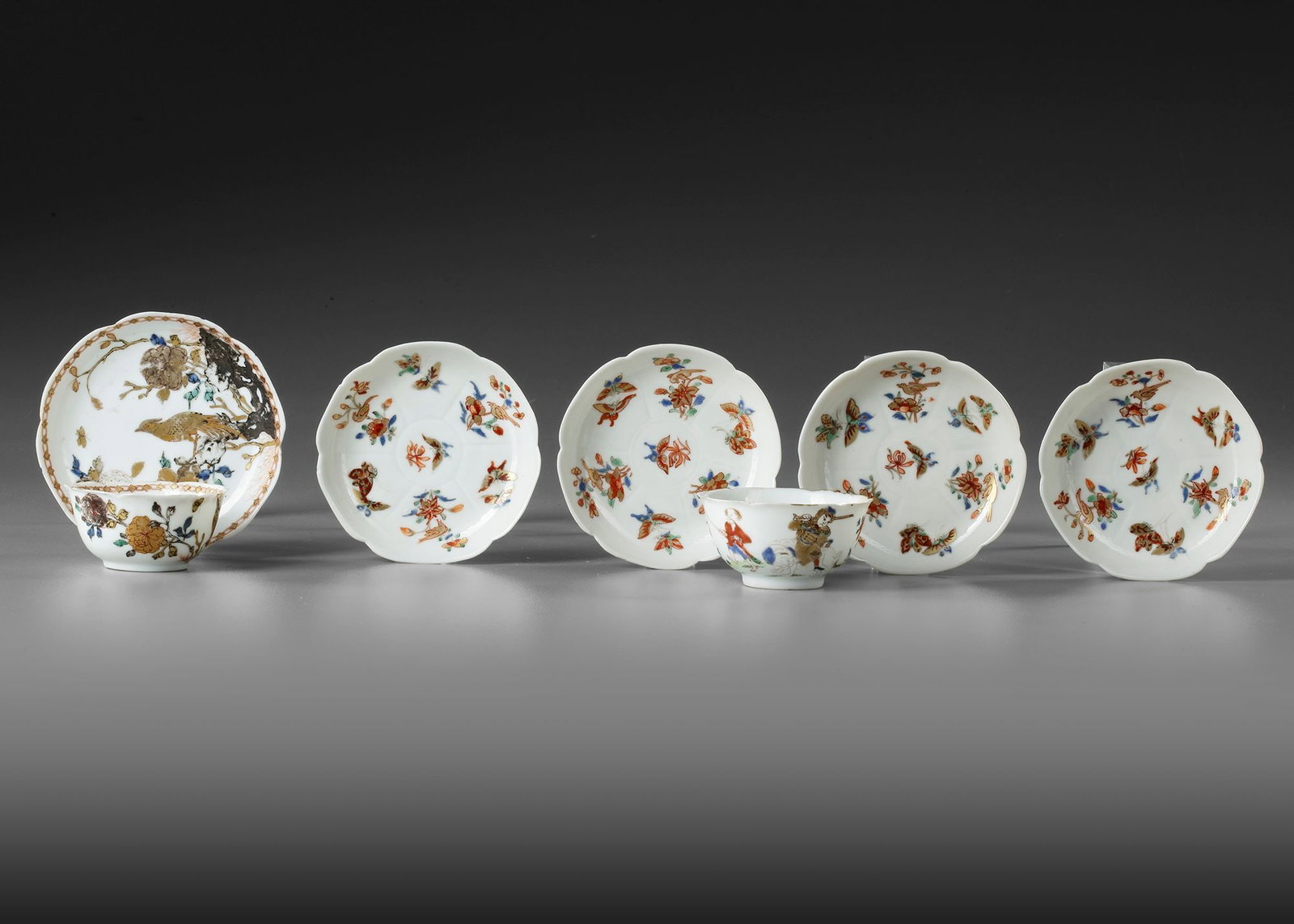 A CHINESE COLLECTION OF TWO CUPS AND FIVE SAUCERS, YONGZHENG PERIOD: A gilt Chinese famille verde cup and saucer, decorated and gilt with an elegant bird perched on a peony blossoming branch growing from ornamental rocks. Height of the cup: 2.9 cm. Diameter of the sauc