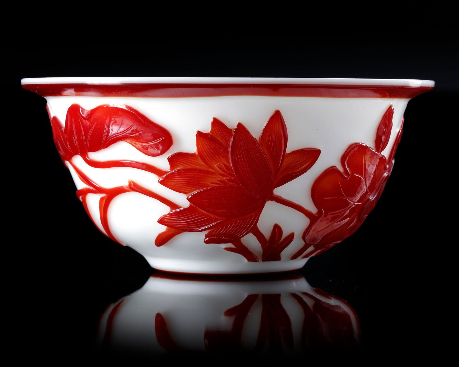 A CHINESE CARVED OVERLAY GLASS FLOWERS BOWL, QING DYNASTY (1644-1911): The bowl is carved to the exterior through the amber glass to depict amongst peonies, all reserved on an opaque milky white ground. Diameter 8 by 17 cm.