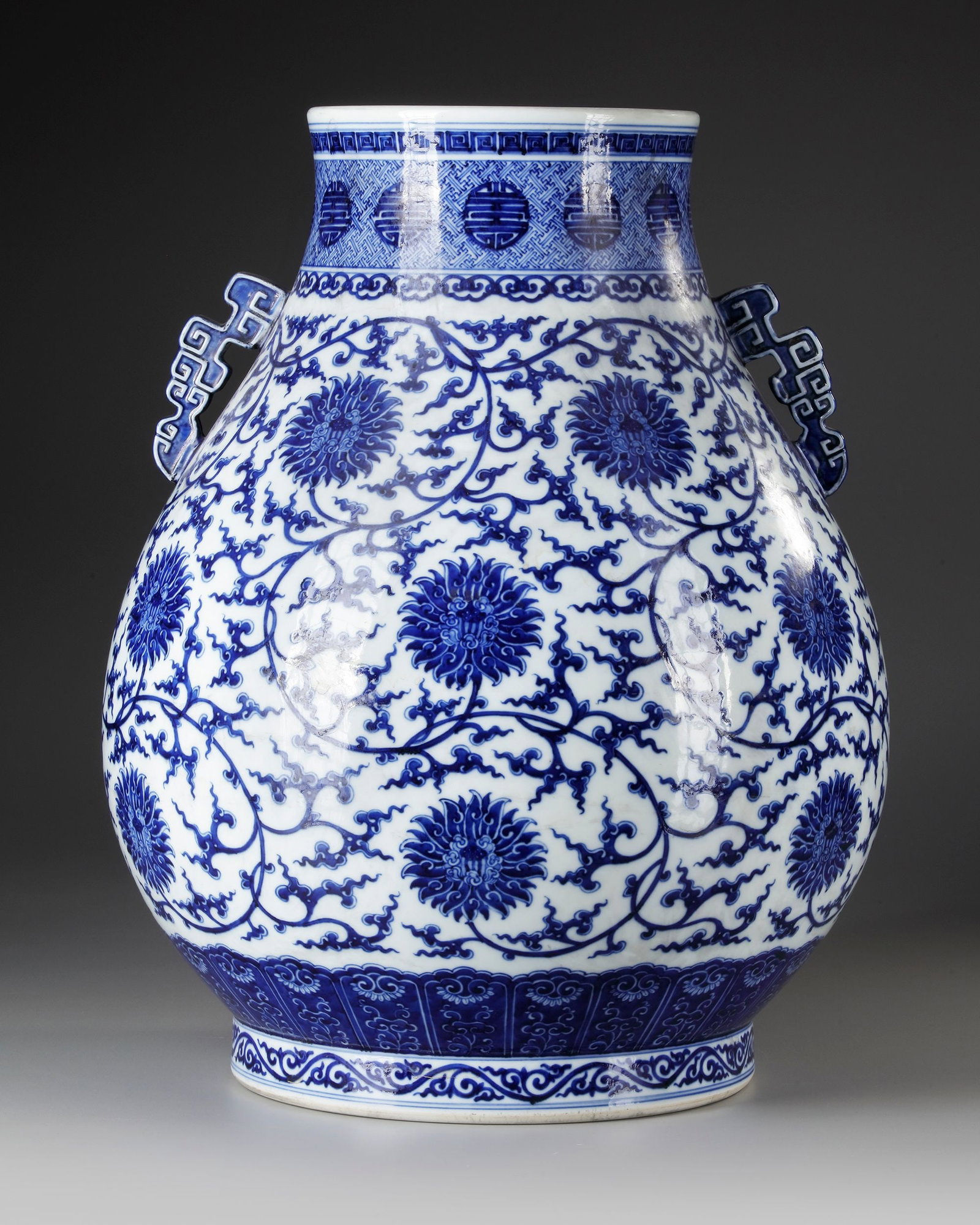 A LARGE CHINESE BLUE AND WHITE HU VASE, 19TH-20TH CENTURY: A large Chinese porcelain pear-shaped vase, heavily potted with a wide generous body and two squared archaistic pierced handles on the shoulder, the body painted with a continuous meander of tendrils 