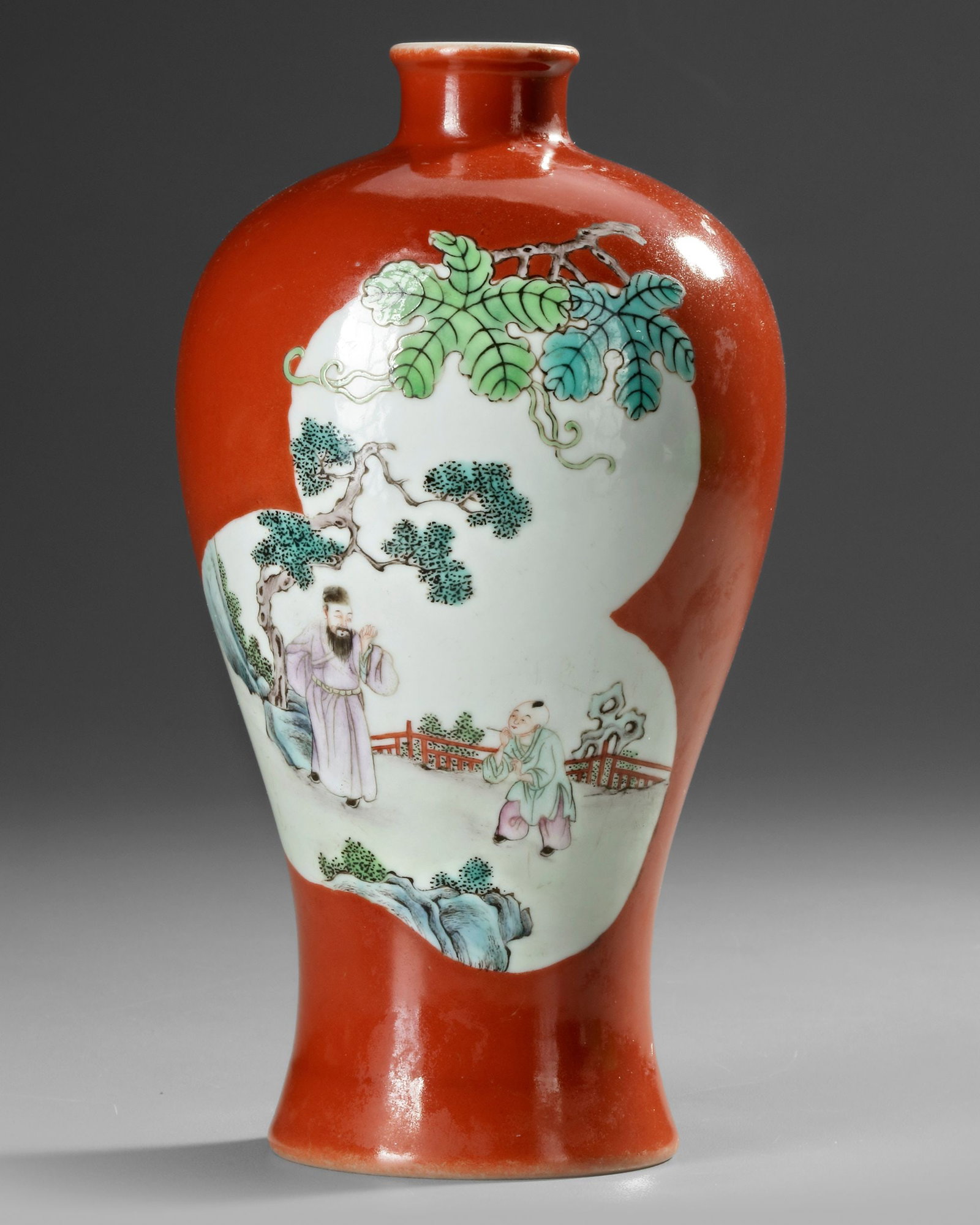 A CHINESE FAMILLE ROSE MEIPING VASE, 20TH CENTURY: A Chinese meiping porcelain vase, covered with a coral-red glaze and decorated in famille rose enamels, featuring two pomegranate-shaped panels, each depicting a scholar with a child under a pine tree