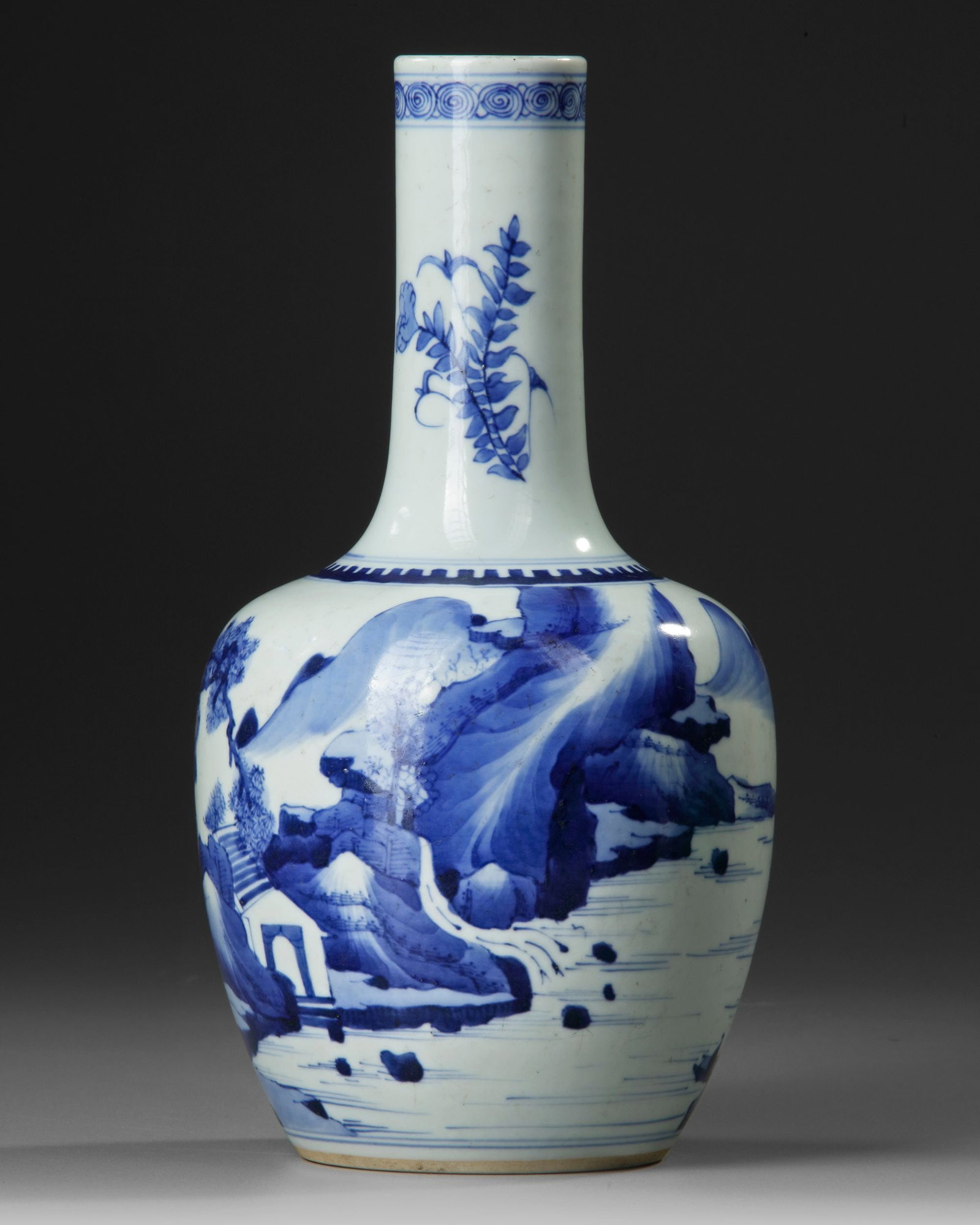 A CHINESE BLUE AND WHITE BOTTLE VASE, QING DYNASTY (1644-1911): The body decorated with a landscape and figural scene, the neck with flower sprays. The base decorated with a double blue ring. Height 28 cm.
