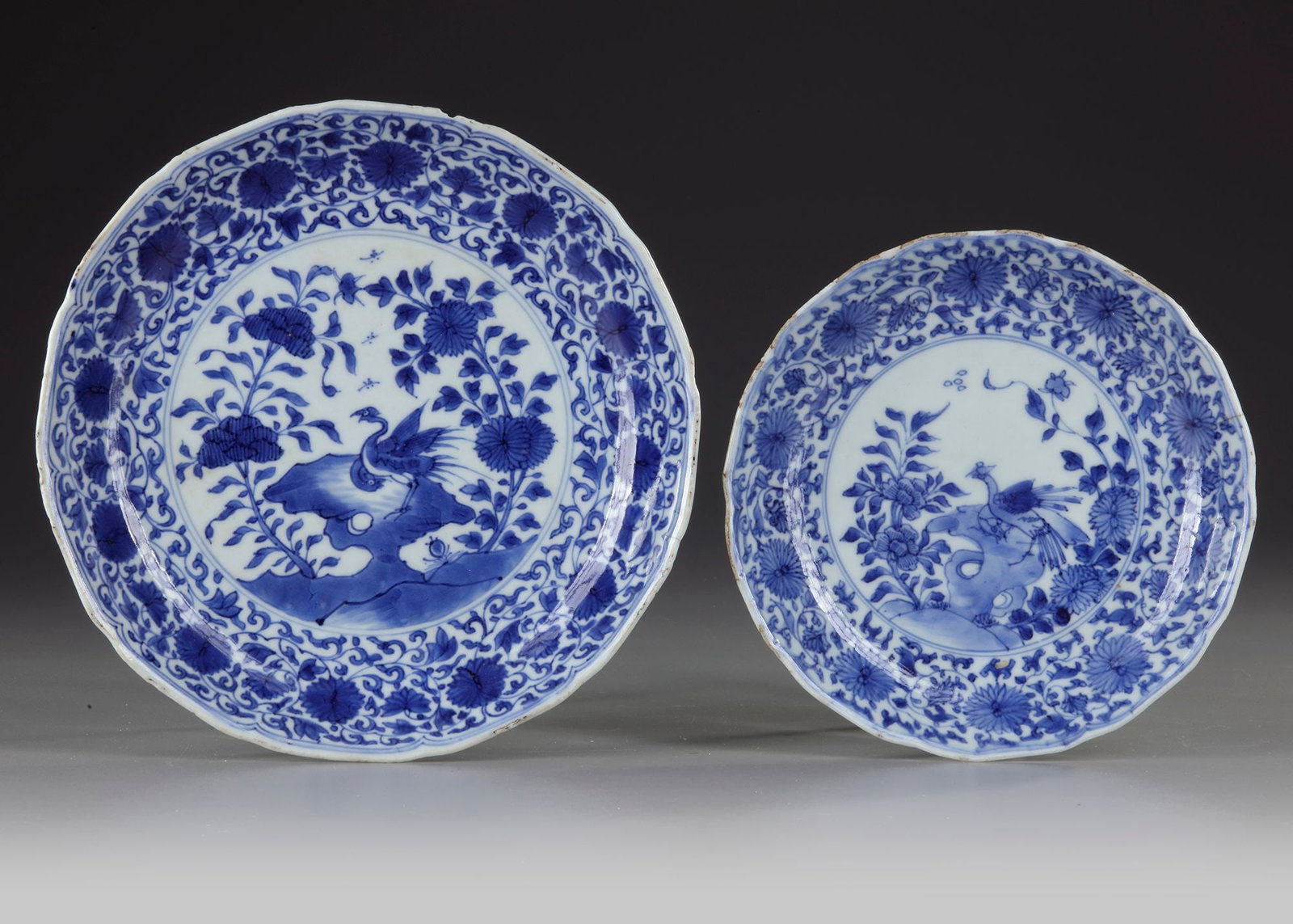 TWO CHINESE BLUE AND WHITE DISHES, KANGXI PERIOD (1662-1722): Both decorated in cobalt-blue with a bird perched on rocks amidst flower branches. Diameter 17.4 and 21.4 cm. Both dishes with a hairline of 3 cm.