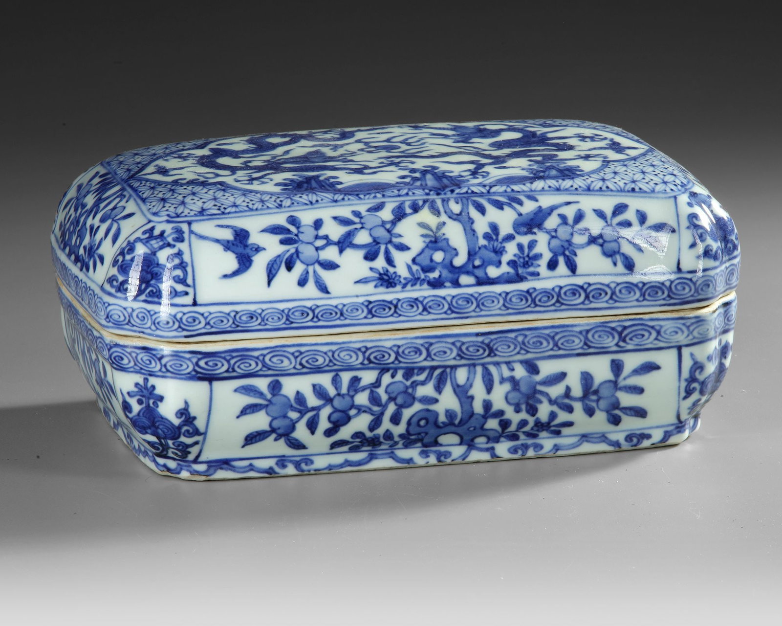 A CHINESE BLUE AND WHITE RECTANGULAR DRAGON BOX AND COVER, QING DYNASTY (1644â€“1911): Of rectangular form with canted corners, decorated in vibrant tones of cobalt-blue to the cover with a rectangular panel enclosing two five-clawed dragons in mutual pursuit of a 'flaming pearl' amidst