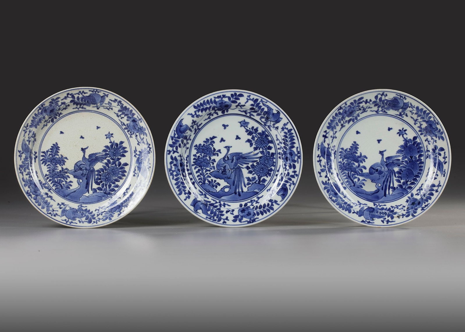 THREE JAPANESE KAKIMON-STYLE BLUE AND WHITE DISHES, 17TH CENTURY: On footring with a flat rim. On the base four spur-marks in a Y-pattern. Decorated in underglaze blue with two birds perched on a rock amongst chrysanthemums and peonies. On the sides and rim a border