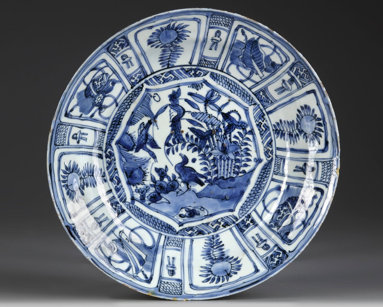 A CHINESE BLUE AND WHITE 'BIRDS' 'KRAAK PORCELAIN' DISH, WANLI PERIOD (1572-1620): The dish is finely decorated to the centre with a star-shaped panel enclosing a bird perched on a rock below further two birds in flight in a lake scene, all surrounded by further lappet-shaped panels