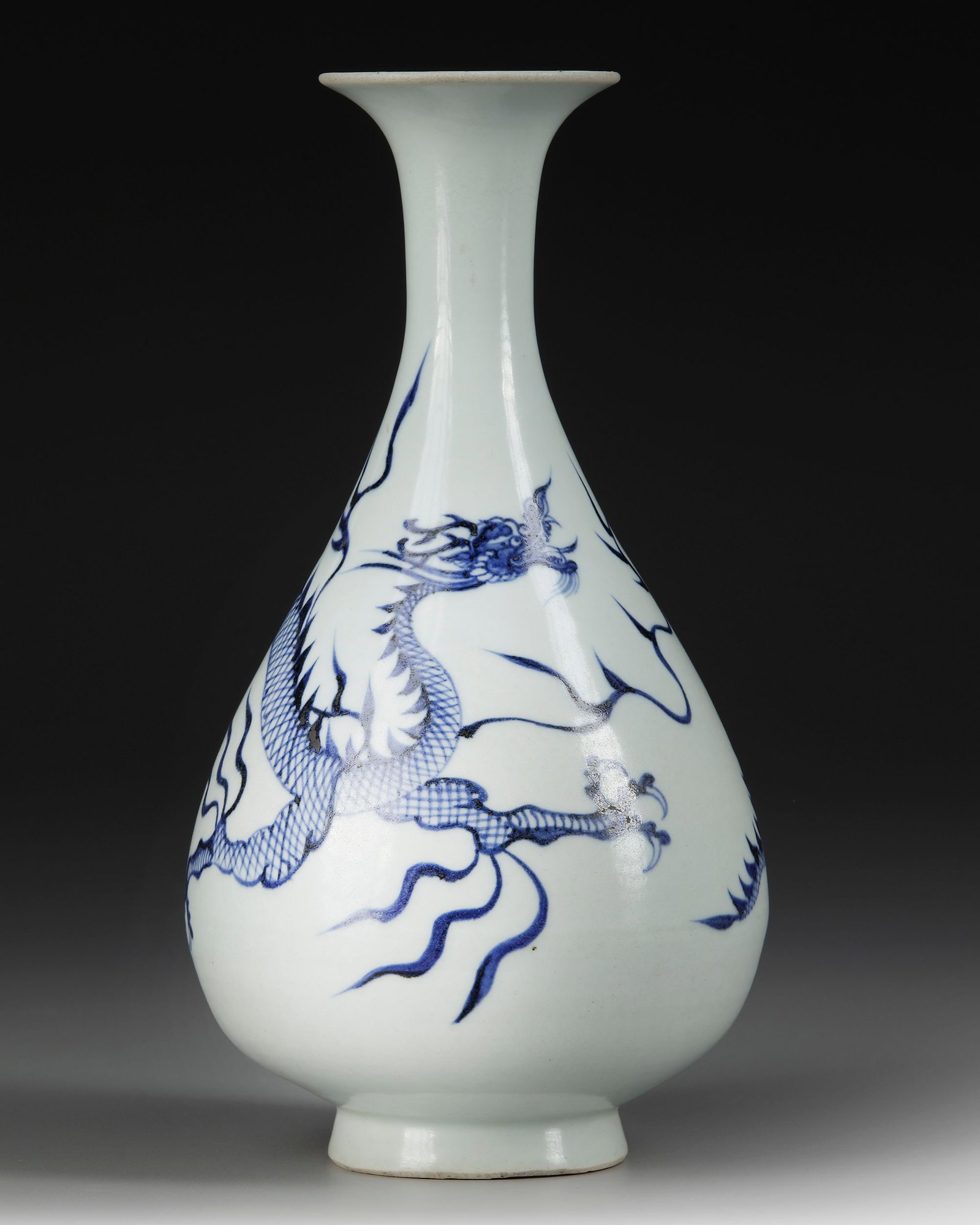 A CHINESE BLUE AND WHITE DRAGON VASE, QING DYNASTY (1644-1911): The full, pear-shaped body raised on a short, slightly spreading foot, rising to a slender neck and widely everted trumpet mouth, freely painted in vivid tones of purplish-blue cobalt with a powerful 