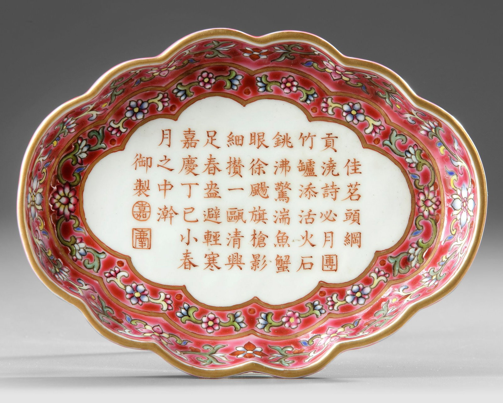 A CHINESE FAMILLE ROSE LOBED TEA TRAY, 19TH-20TH CENTURY: The tray has shallow rounded sides raised on four bracket supports, and is painted in the center in iron red with an Imperial poem praising well-prepared tea that is dated to the cyclical year of ding