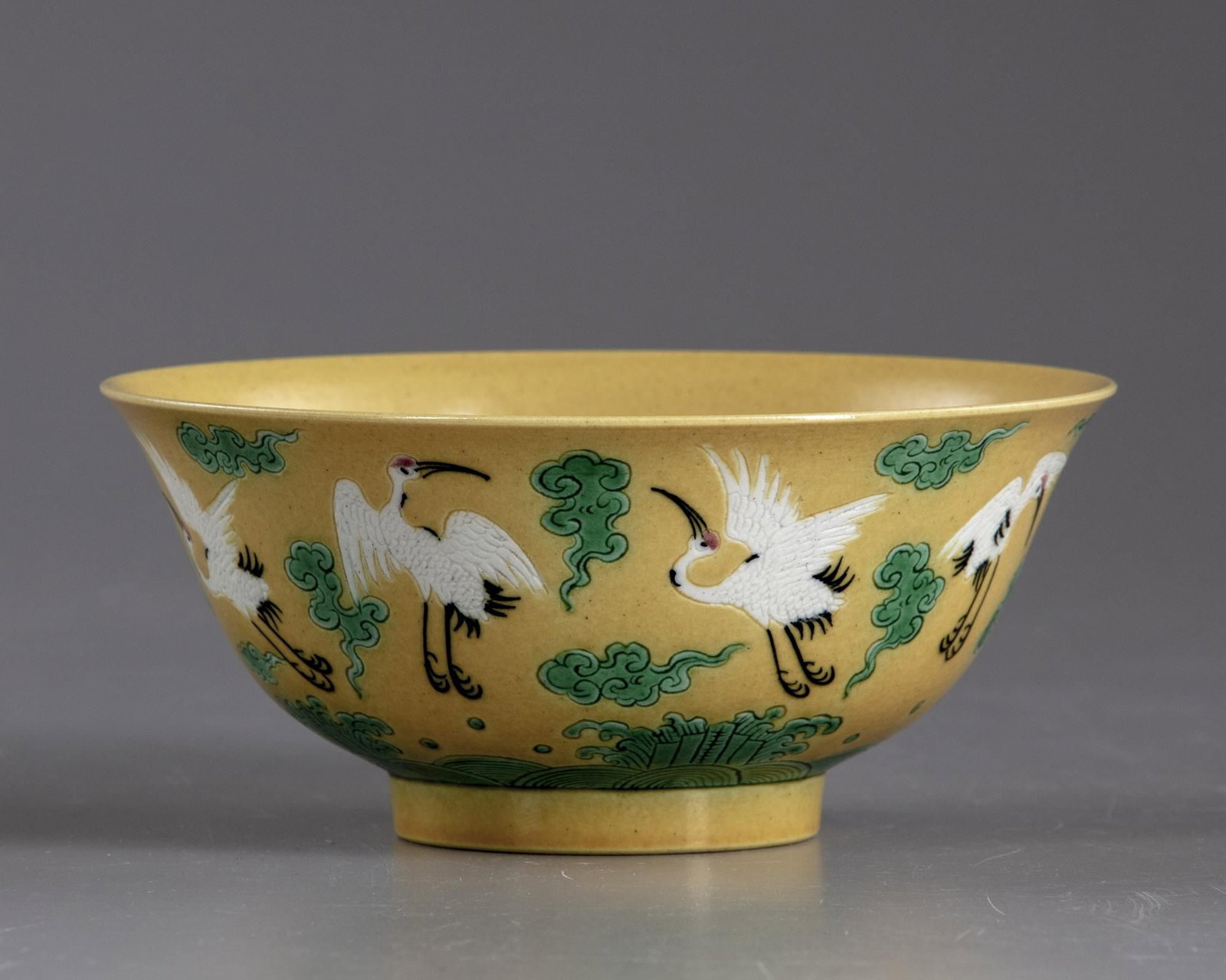 A CHINESE CRANES YELLOW-GROUND BOWL, 20TH CENTURY: A Chinese porcelain bowl, decorated to the interior with a shou symbol surrounded by two cranes and clouds, to the exterior with cranes and clouds above waves. The bottom with a Chinese Yongzheng six 