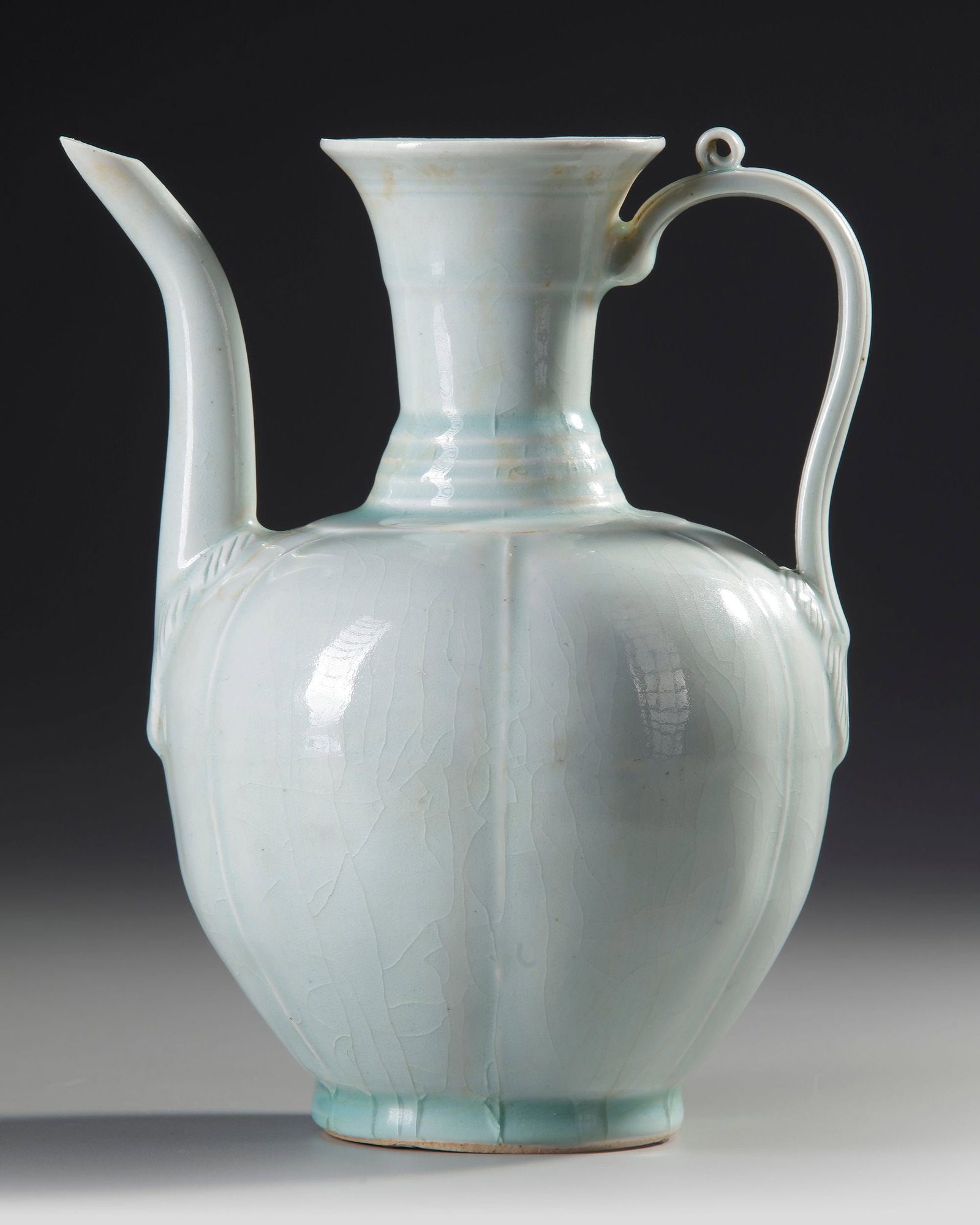 A CHINESE QINGBAI MELON-FORM EWER, SONG DYNASTY (960-1279 AD): A Chinese porcelain ewer, potted with an six-lobed body rising to a tall cylindrical neck flaring at the rim, set on one side with a slender, curving spout opposite a strap handle with a small ring at