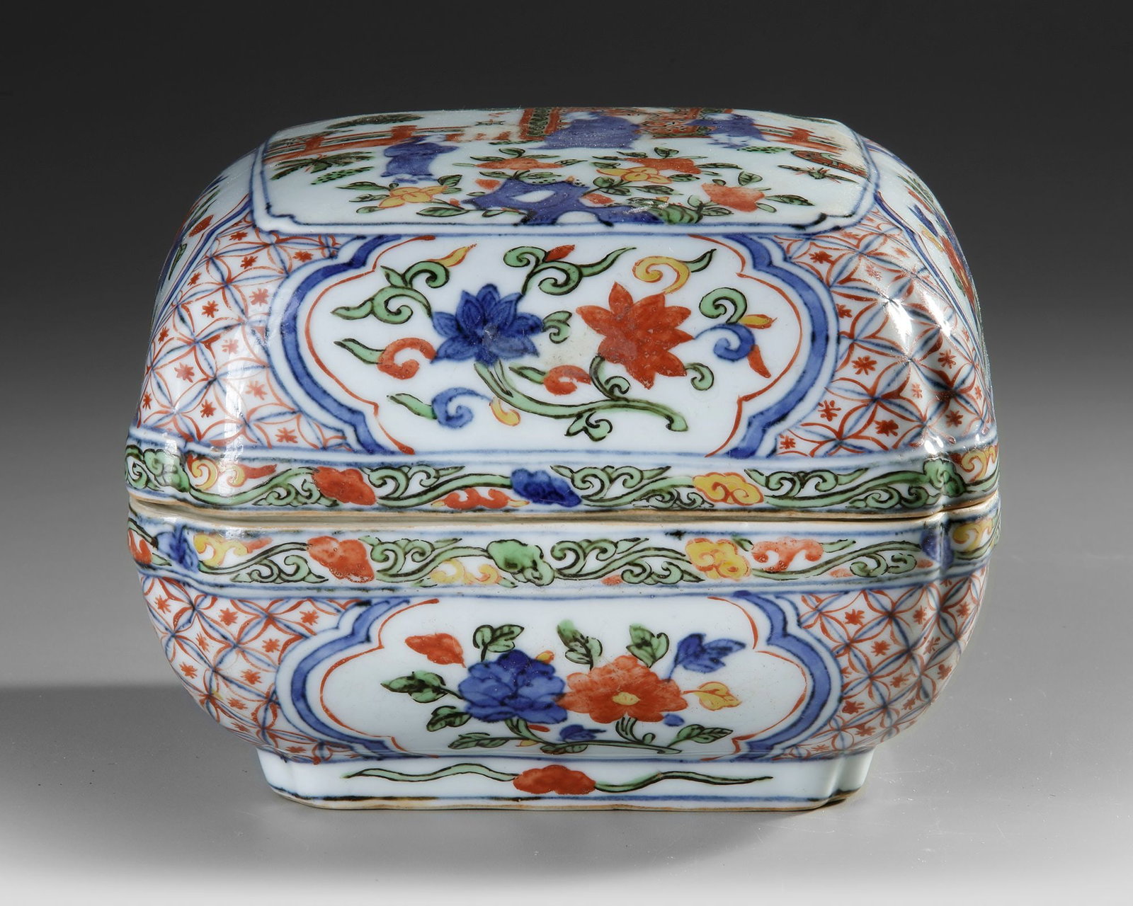 A CHINESE FAMILLE VERTE BOX AND COVER, QING DYNASTY (1644â€“1911): A Chinese porcelain box and cover of square form with chamfered corners, exquisitely decorated with a dignitary and his servants within a fenced garden. The rounded sides of both the box and cover fea