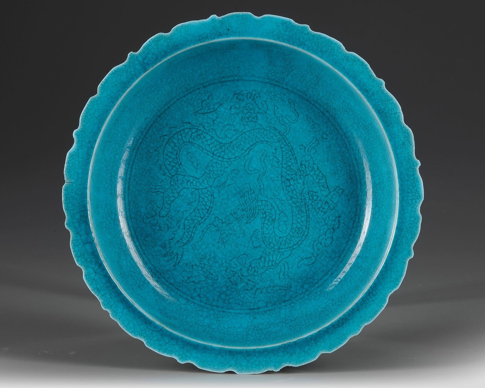 A CHINESE 'DRAGON' TURQUOISE GLAZED DISH, QING DYNASTY (1644â€“1911): A Chinese porcelain dish with an everted barbed rim, covered with a turquoise glaze and decorated with a five-clawed dragon amidst clouds. The base bears a Chinese Hongzhi six-character mark within a 