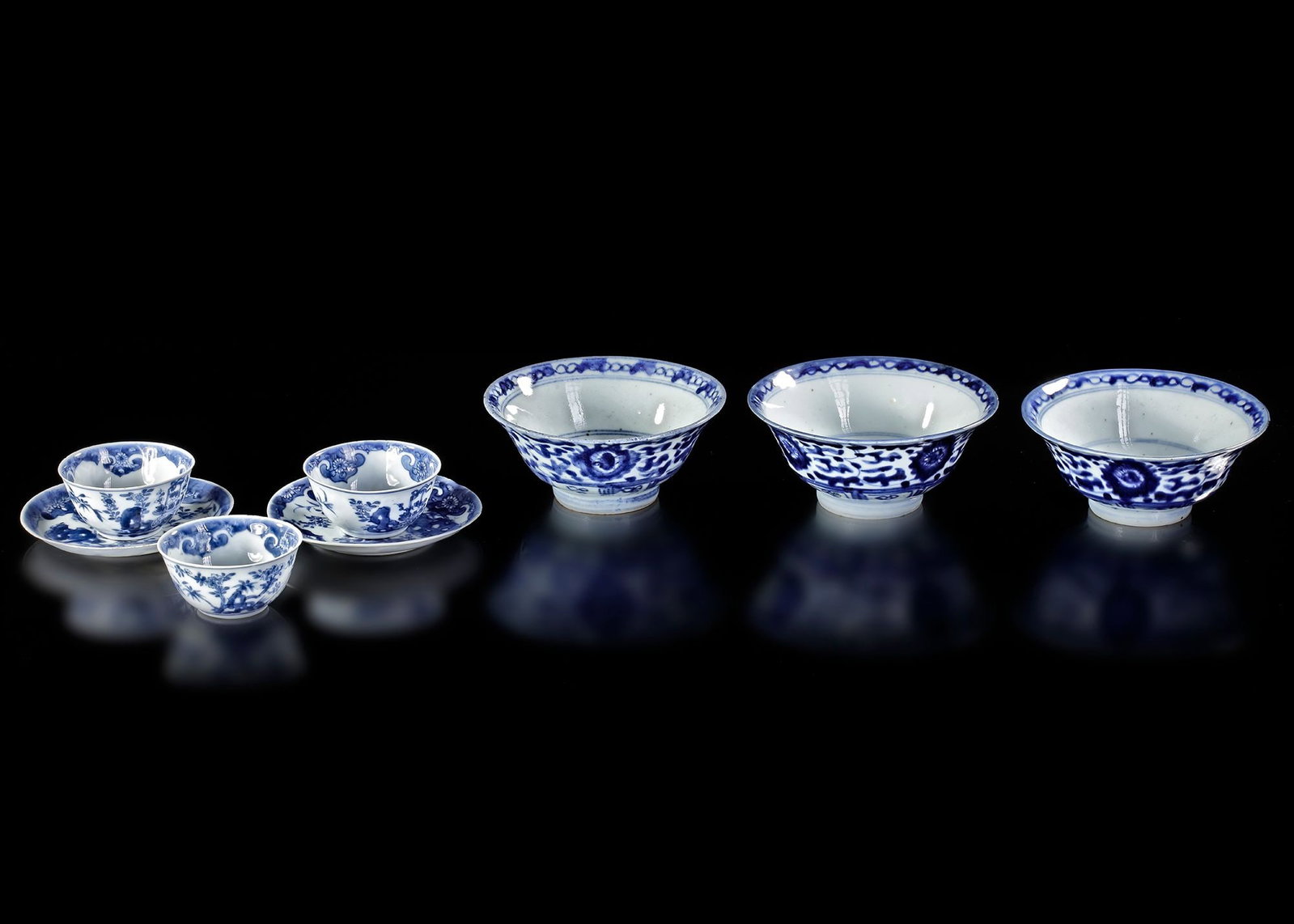 A GROUP OF SIX CHINESE BLUE AND WHITE PORCELAIN VESSELS, 18TH CENTURY: Comprising three small tea bowls with two matching saucers and three larger deep bowls. The tea bowls are decorated in underglaze cobalt blue with floral sprays within diaper-pattern borders. The acco