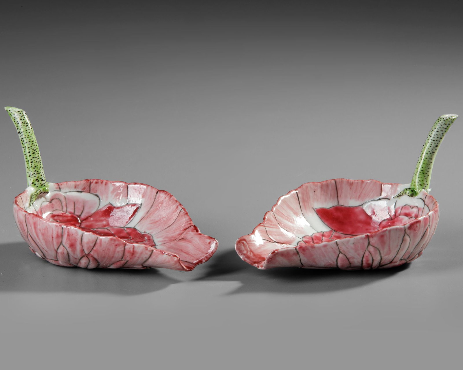 A PAIR OF CHINESE FAMILLE ROSE 'LOTUS' CUPS, 19TH-20TH CENTURY: Each modeled in the shape of a large lotus blossom with incised overlapping petals outlined in black enamel and filled with shades of pink, the outer row of petals rising to form the gently flared wal