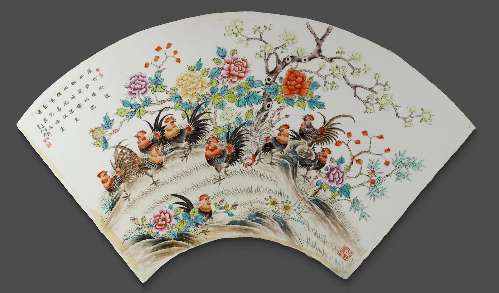 A CHINESE FAMILLE ROSE PLAQUE, 20TH CENTURY: A Chinese porcelain fan shaped panel, decorated in famille rose enamels with cockerels amidst peony blossoming branches. 35 by 70 cm.