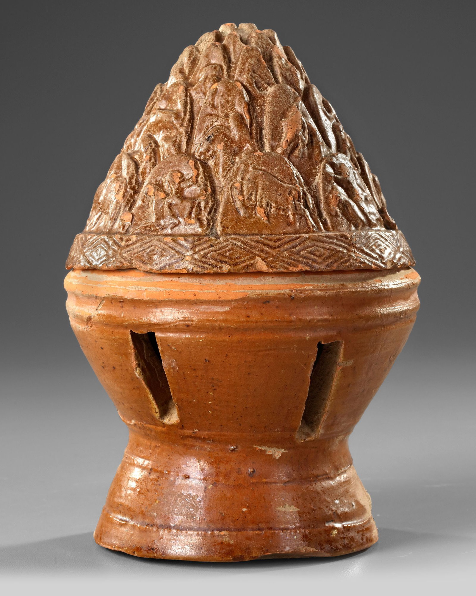 A CHINESE BROWN GLAZED BURNER, EASTERN HAN DYNASTY (25-220 AD): A brown glazed burner and cover in the form of a mountain. Height 22 cm.