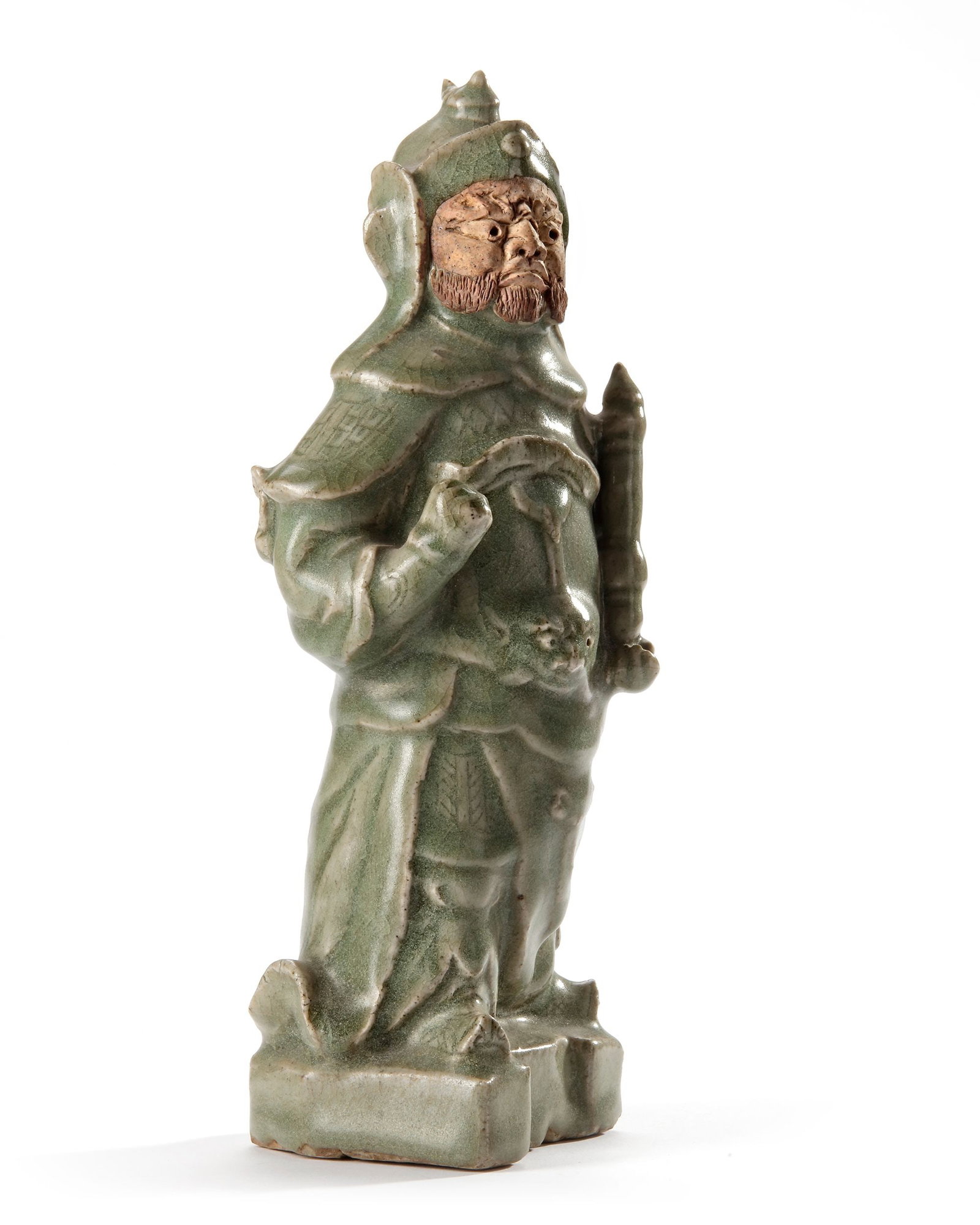 A CHINESE CELADON GUAN YU FIGURE, MING DYNASTY, 15TH CENTURY: A Chinese celadon figure of the god of war, Guan Yu, covered with a light green glaze to the foot, semi-hollow base with an unglazed foot-rim burnt red, face left in biscuit. Height 24.8 cm.