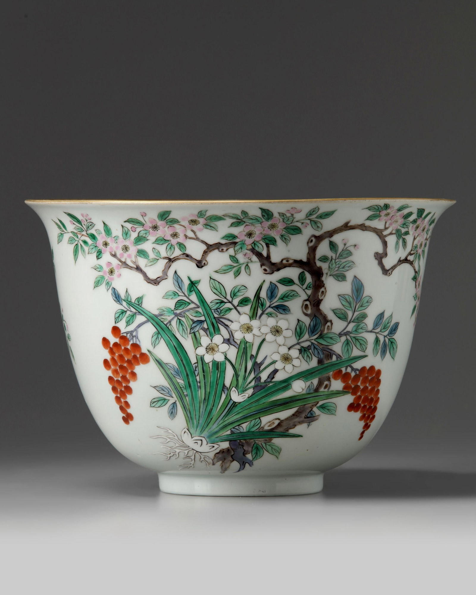 A LARGE JAPANESE 'FLORAL' BOWL, 19TH CENTURY: The bowl is decorated to the body with a flowering prunus tree with large bunches of nandina berries and narcissus. The interior rim is decorated with a thick blue-enamelled band. The base with a gree