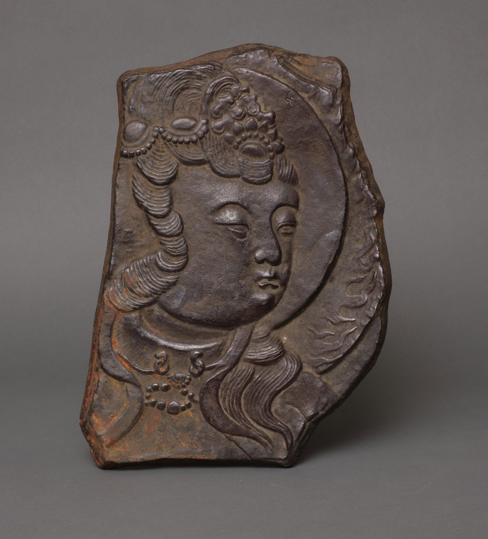 A LARGE JAPANESE PLAQUE BODHISATTVA KANNON, EARLY-MID 20TH CENTURY: Cast iron plaque showcasing a portrait of the bodhisattva Kannon en-profile in relief. Kannon is the Goddess of Mercy, also known as Avalokiteshvara or Guanyin. Length 36.5 cm, Width 25.5 cm, Depth 2 