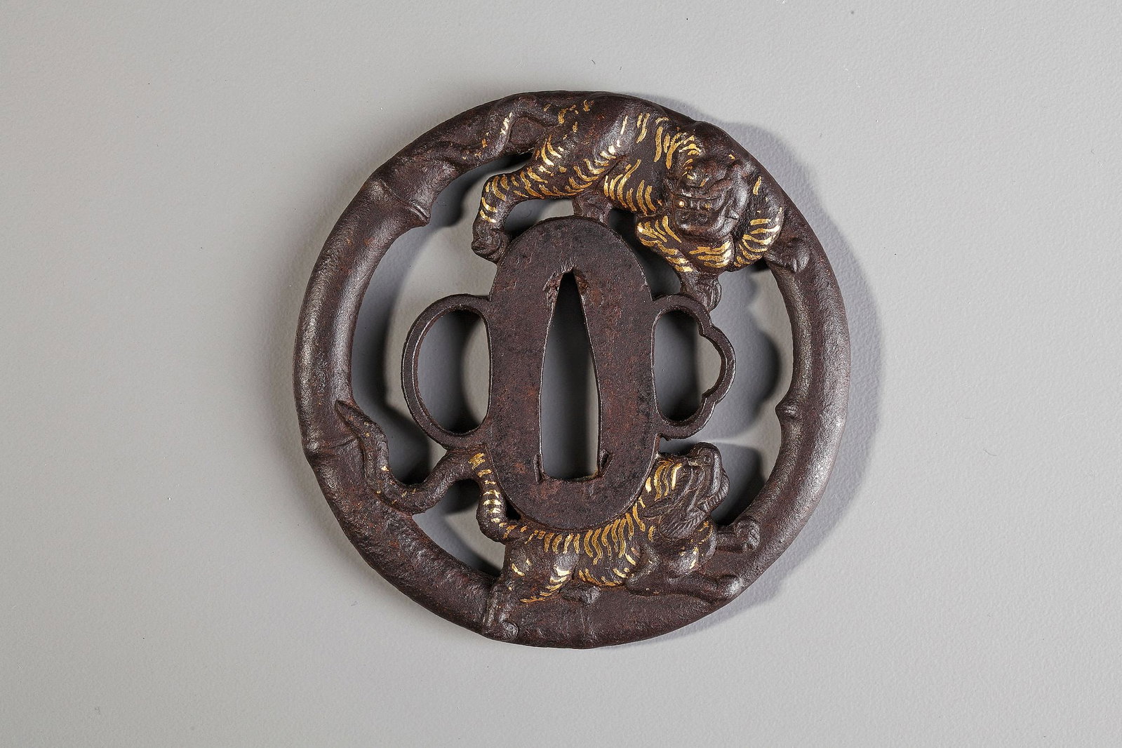 A JAPANESE TSUBA,EDO PERIOD (1615â€“1868): Of round form, carved and pierced in the shape of two mythical creatures, inlaid with gold, the outer ring shaped like bamboo. Diameter .7.40 cm.