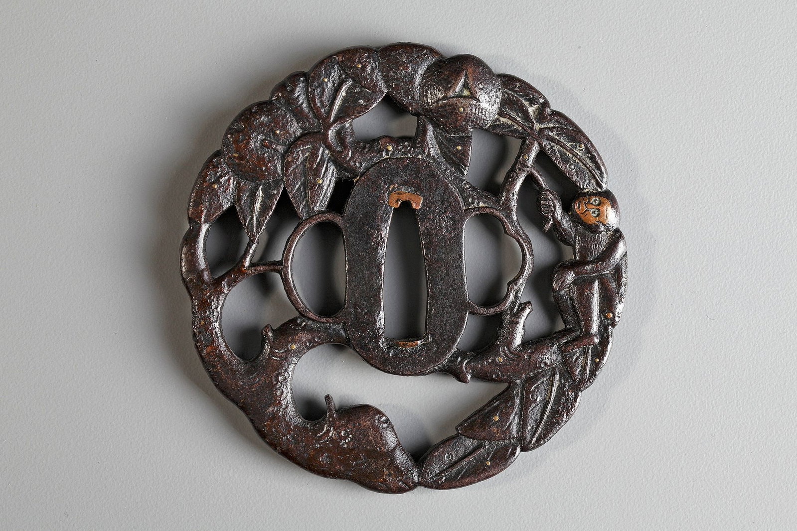 A JAPANESE TSUBA,EDO PERIOD (1615â€“1868): Of rounded form, carved and pierced in shape of a small monkey sitting in a fruit bearing persimmons tree. Diameter .8.20 cm.