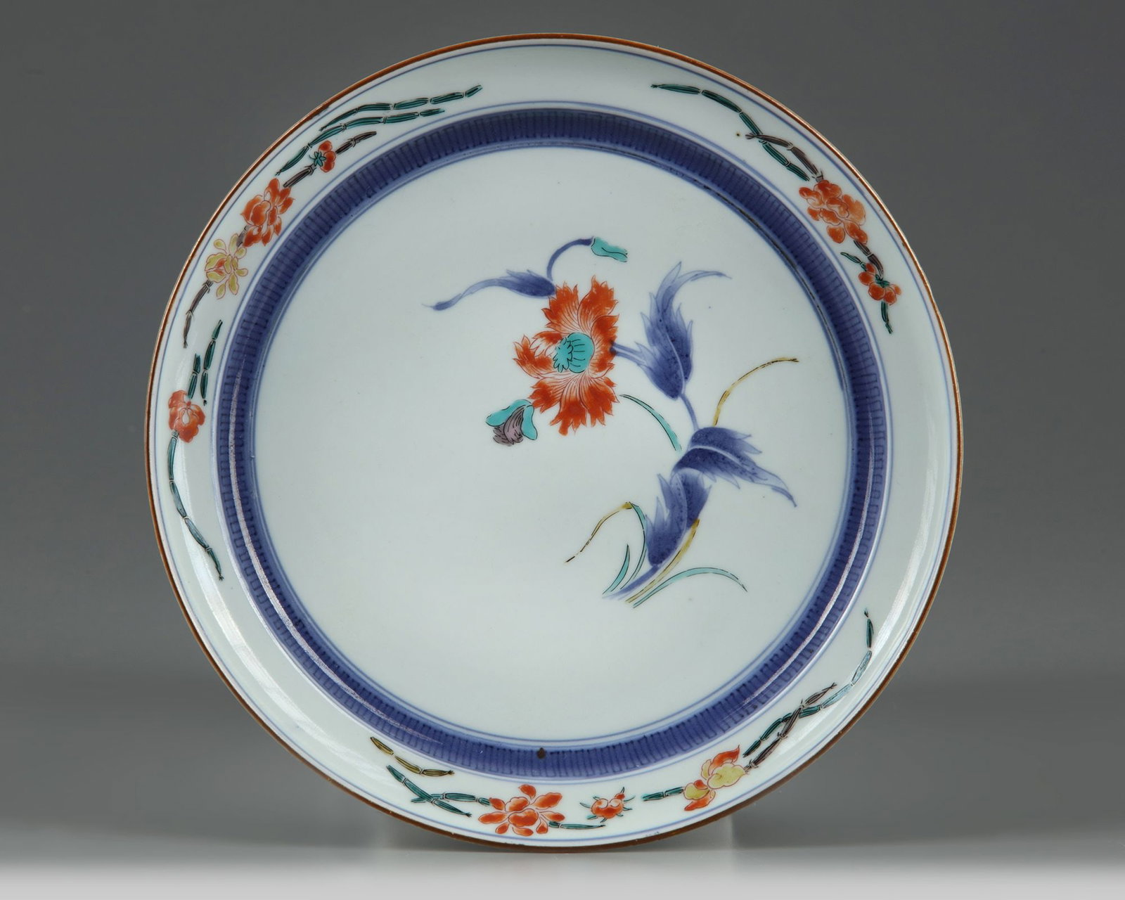 A JAPANESE KAKIEMON DISH, 17TH CENTURY: Stands on a small footring, decorated in Kakiemon enamels with large flowering branches, to the exterior with flower scrolls. Diameter 21 cm.