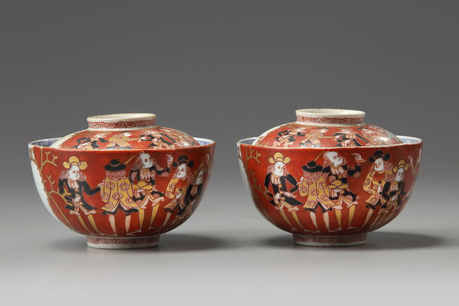 A PAIR OF JAPANESE IMARI NANBAN SHIP BOWLS AND COVERS, 19TH CENTURY: The bowls decorated to the exterior in Imari enamels with European figures and a ship. The interior in blue and white with flowers and foliage. Height 6 cm. Diameter 11 cm.