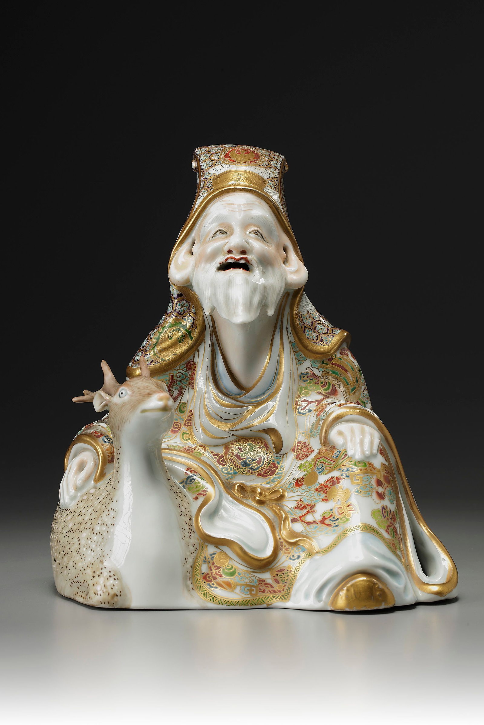 A JAPANESE SATSUMA FIGURE OF SEATED JUROJIN AND A DEER, MEIJI PERIOD (1868-1912): Japanese Satsuma figure of a seated Jurojin (one of the seven lucky gods) and a deer. Height 22 cm.