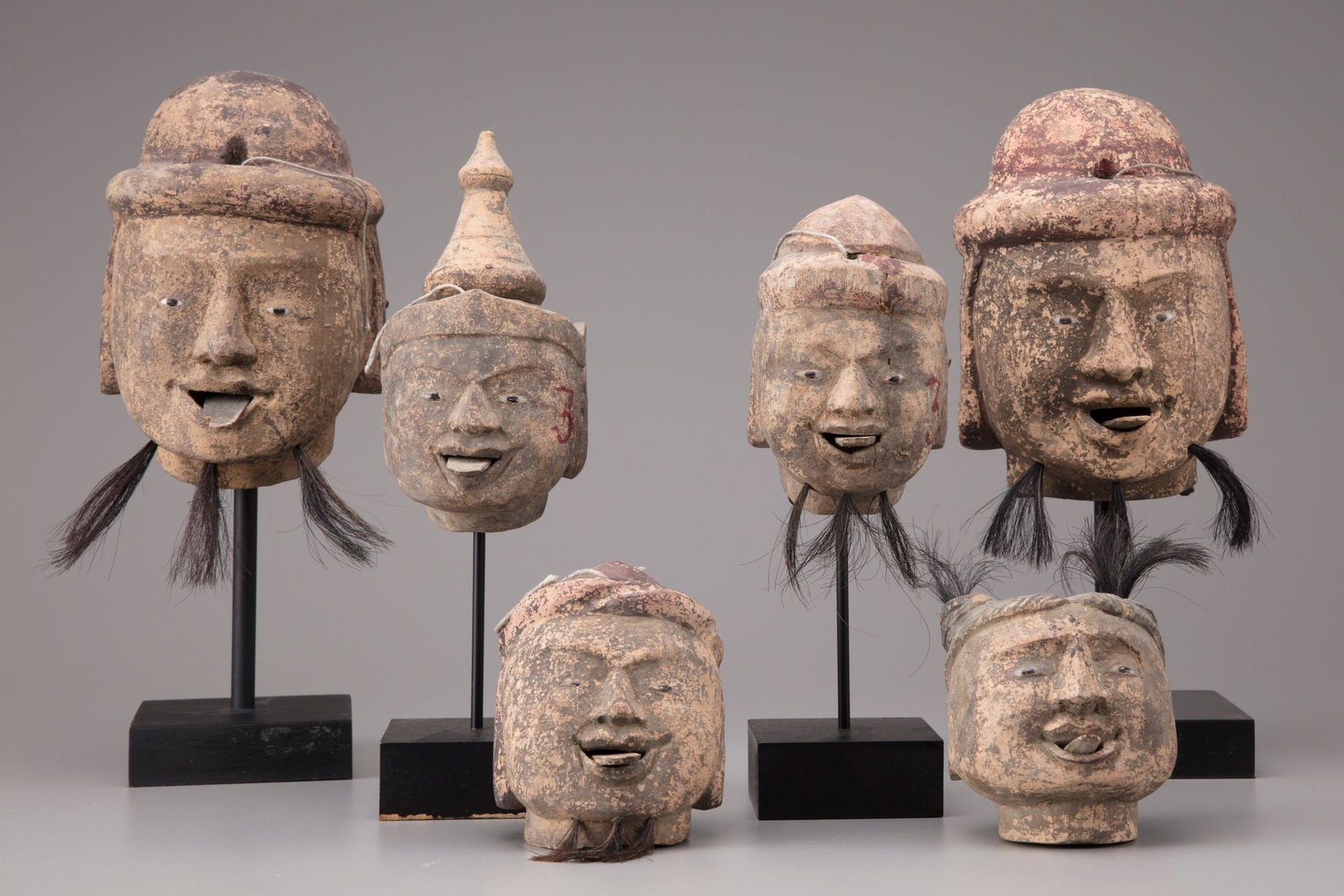 SIX BURMESE WOODEN PUPPETS HEADS, 20TH CENTURY: Carved wood, retractable tongue, painted stone eyes and pigs hair. 23 cm. and smaller.
