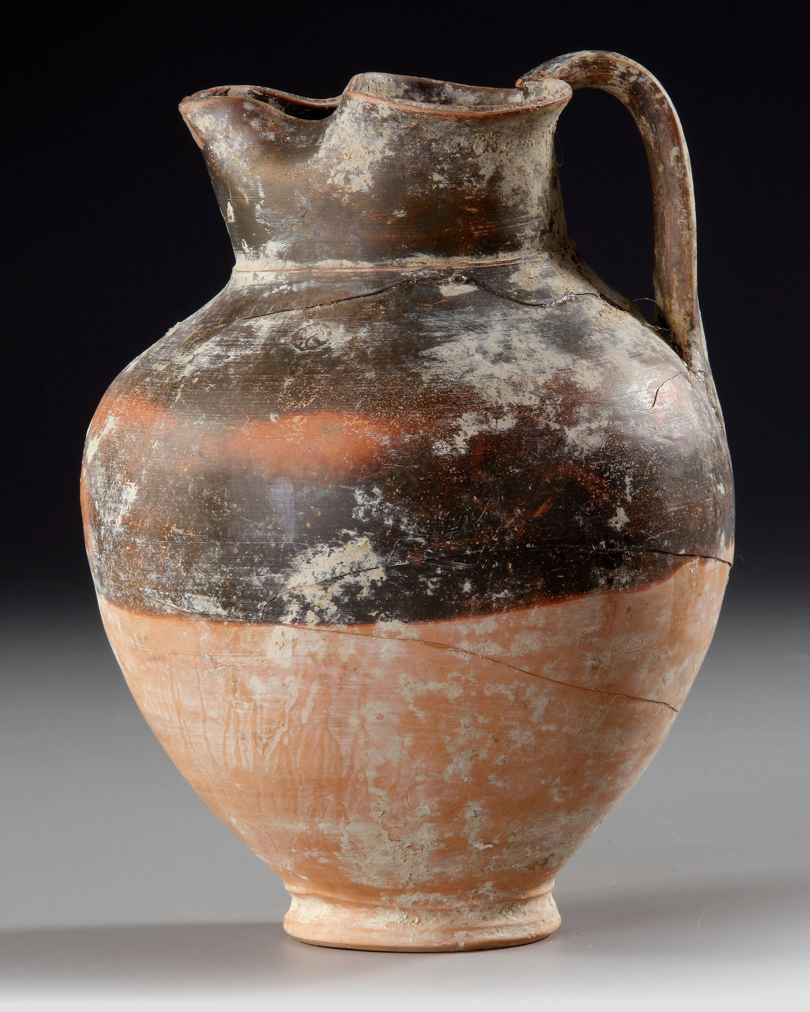 A GREEK OINOCHOE, RED AND BLACK, 3RD - 2ND CENTURY BC: Height 23 cm.