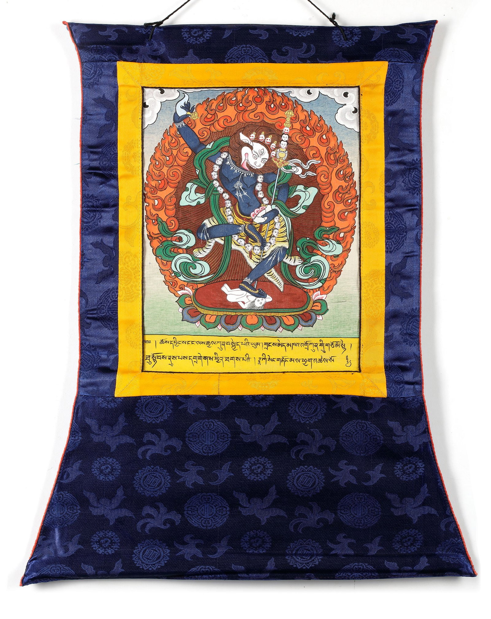 A WRATHFUL BUDDHIST DEITY THANGKA, TIBET, 20TH CENTURY: A vibrant Tibetan thangka depicting a wrathful Buddhist protector deity in dynamic dancing posture, surrounded by a halo of flames symbolizing the destruction of ignorance and negative forces. Richly 