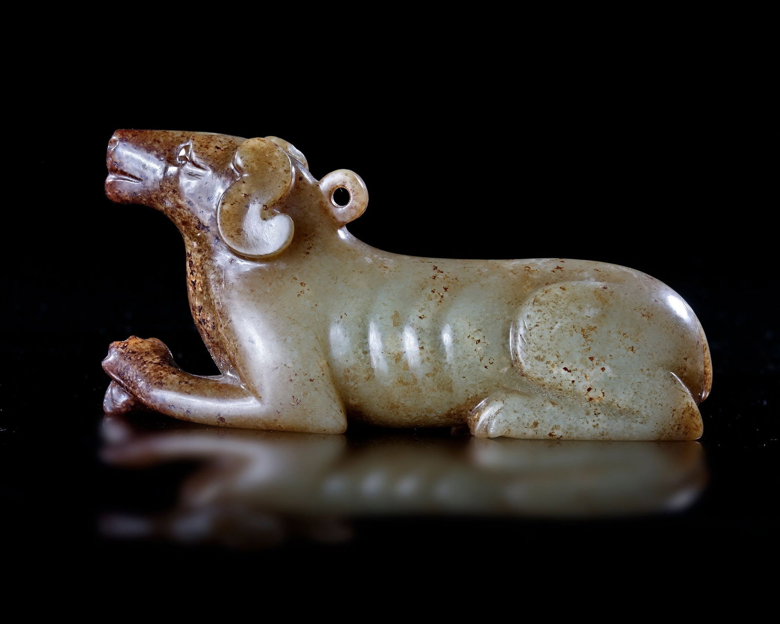 A CHINESE JADE OF A RECLINING DOG, HAN DYNASTY (206 BCâ€“220 AD): A finely carved light green jade figure of a reclining dog, rendered with elegant simplicity and naturalistic form. The animal rests alertly with folded legs and a raised head, while subtle incised de