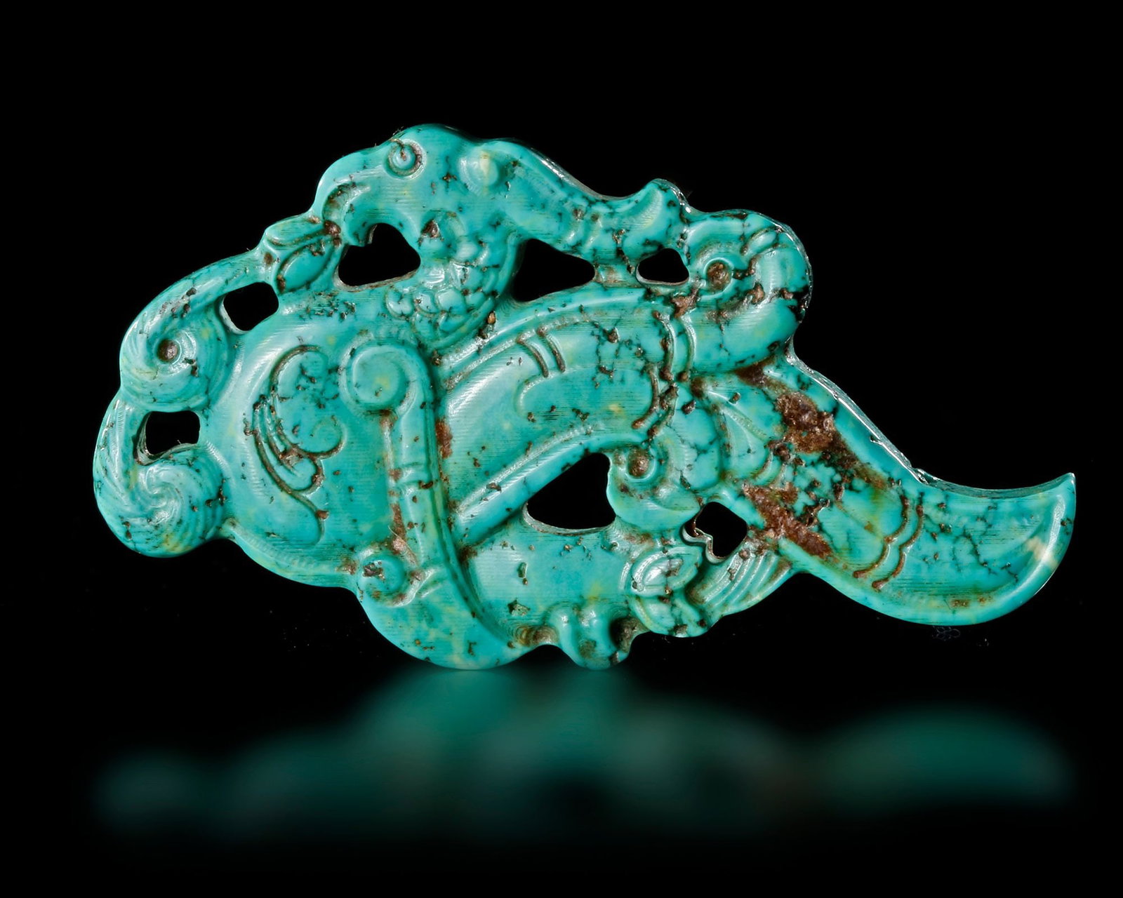 A TURQUOISE BIRD AND SERPENT PENDANT, CHINA, ZHOU PERIOD (770â€“256 BC): An exceptional turquoise pendant carved in the form of a mythical bird grasping a serpent, symbolizing power, protection, and transformation. The openwork design is richly detailed with flowing scroll
