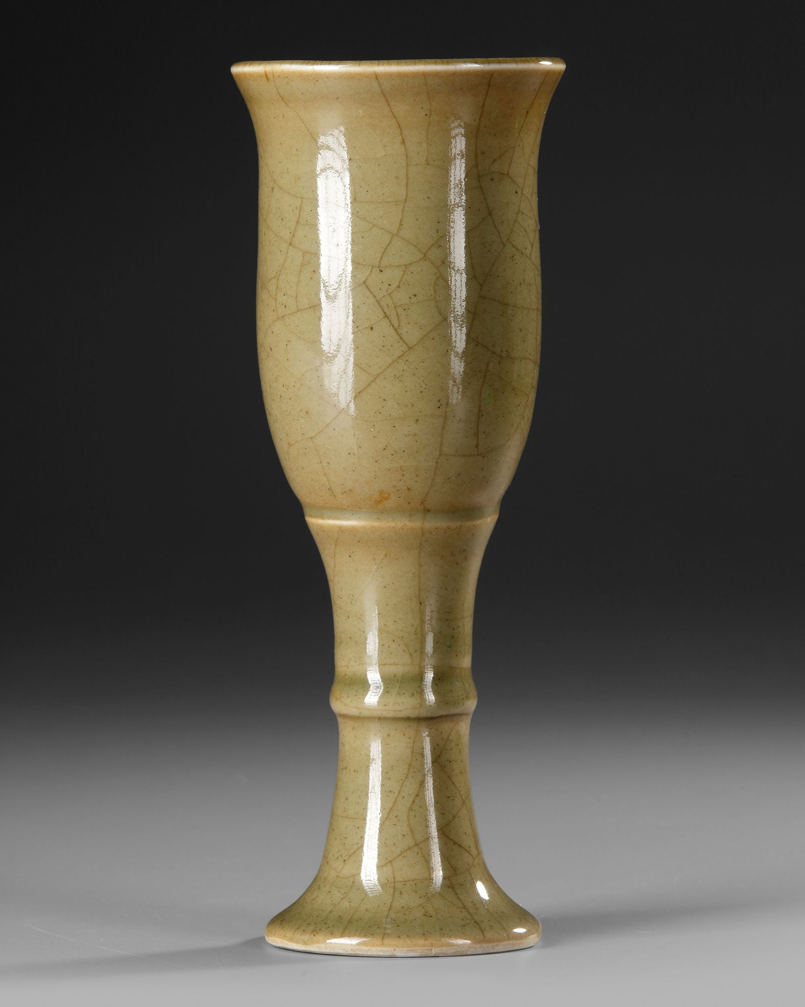 A CHINESE QIANLONG CELADON-GLAZED STEM CUP, QIANLONG MARK AND OF THE PERIOD: A finely potted Chinese porcelain stem cup, of elegant waisted form, rising from a spreading trumpet foot to a tall, gently tapering body with an everted rim, covered overall in a warm crackled celado