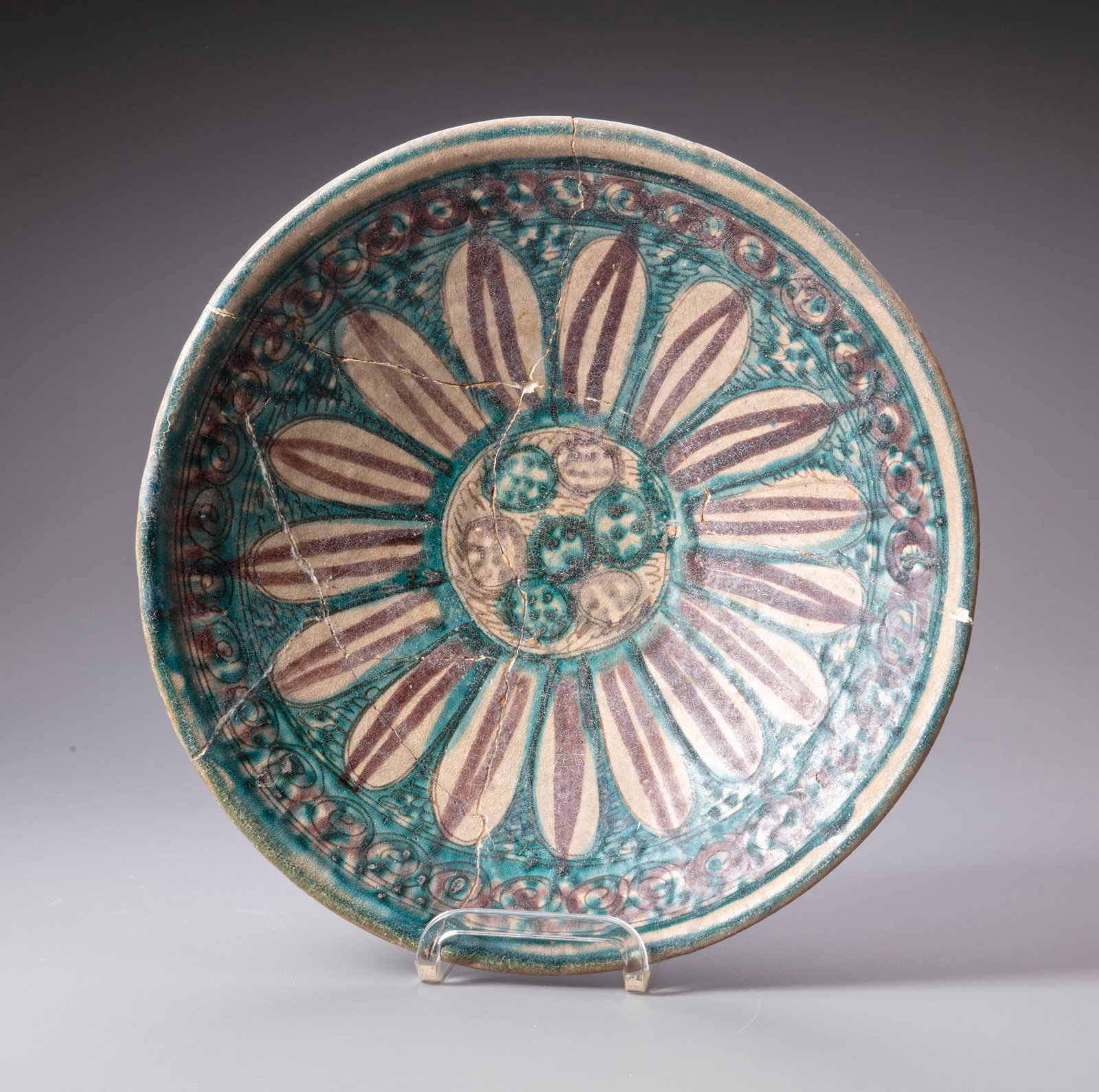 A LARGE TURQUOISE-GLAZED POTTERY BOWL PERSIA, NISHAPUR 12TH CENTURY: A large Persian pottery turquoise-glazed bowl, decorated in manganese and black with radiating elongated petal motifs around a central medallion, enclosed by scrolling ornament and a decorative border
