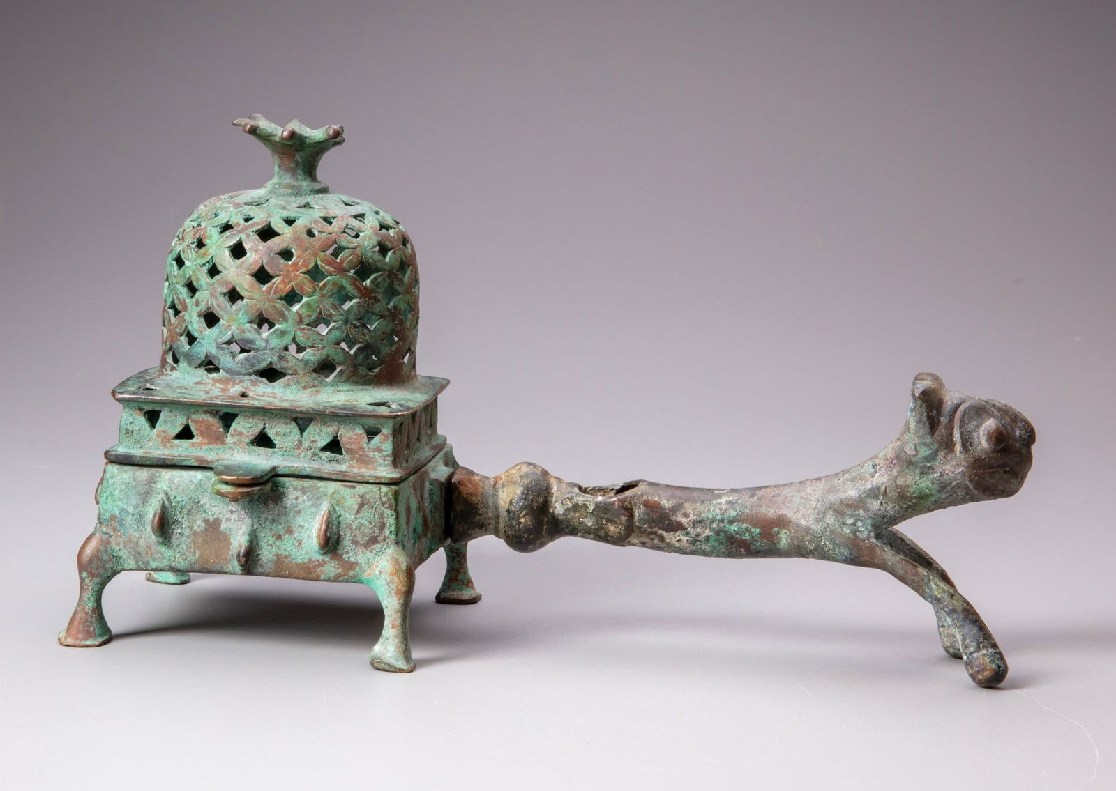 A PERSIAN BRONZE INCENSE BURNER, PERSIA 12TH CENTURY: A finely cast bronze incense burner of rectangular form, raised on four short feet and surmounted by a pierced domed cover with openwork decoration and a distinctive finial. The vessel is fitted with 