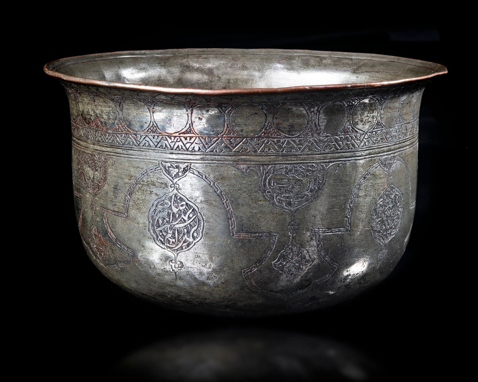 A SAFAVID TINNED-COPPER BOWL, PERSIA 16TH CENTURY: A Persian tinned-copper bowl with everted and lipped rim, the incised decoration comprising a band of roundels above cartouches enclosing engraved seated animals. Inscriptions: "Li sahibeh Abraham, to