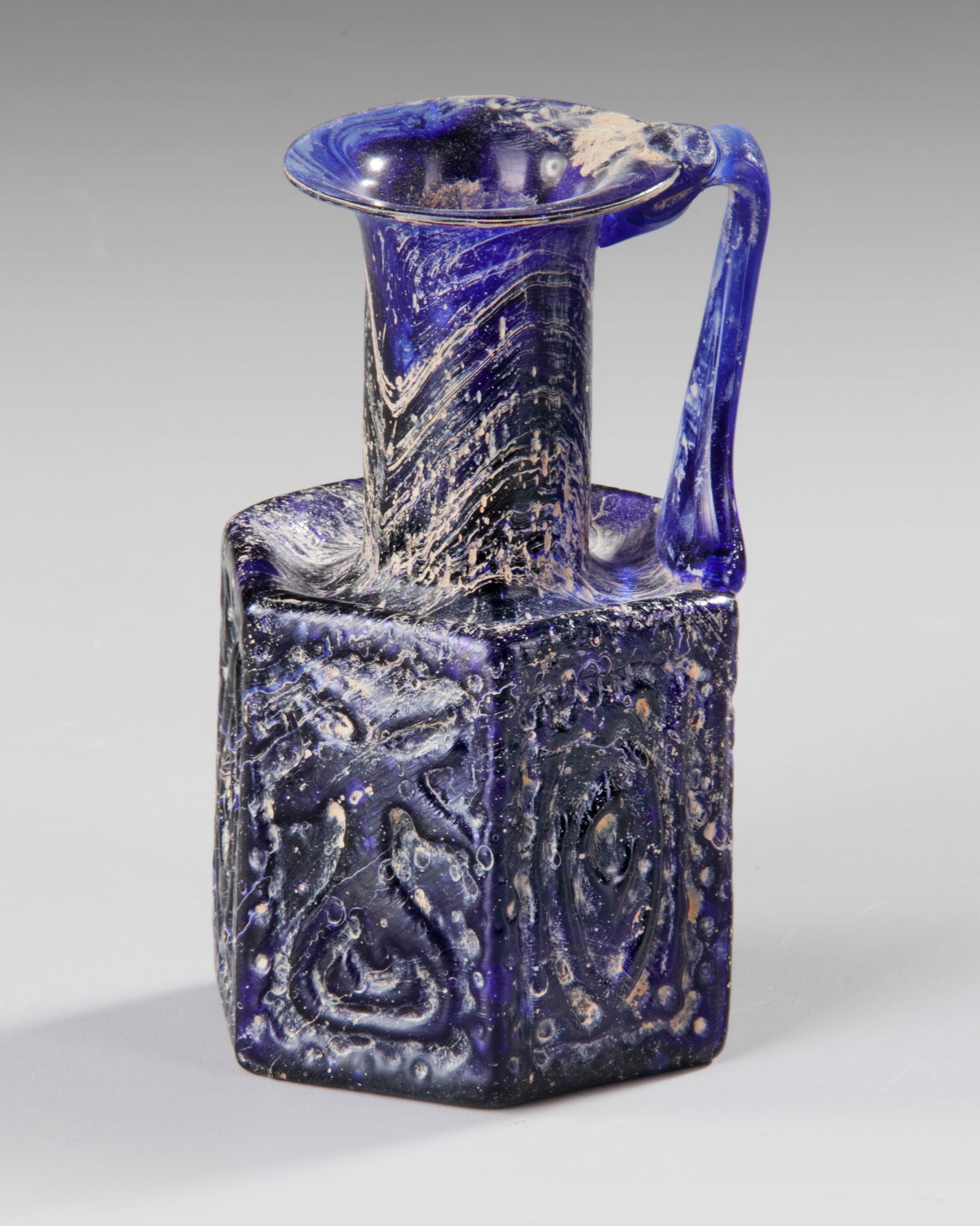 A COBALT BLUE MOLDED GLASS JUGLET, EASTERN MEDITERRANEAN, 1STâ€“3RD CENTURY AD (1 of 4)