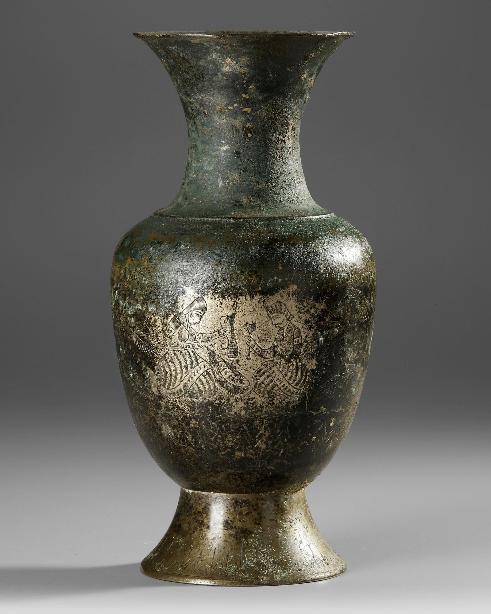 AN INDIAN BRONZE VASE, 17TH-18TH CENTURY: A finely crafted Indian bronze vase from the 17th-18th century, featuring a graceful baluster form with a flaring neck and raised foot. The surface is decorated with delicately engraved figural scenes