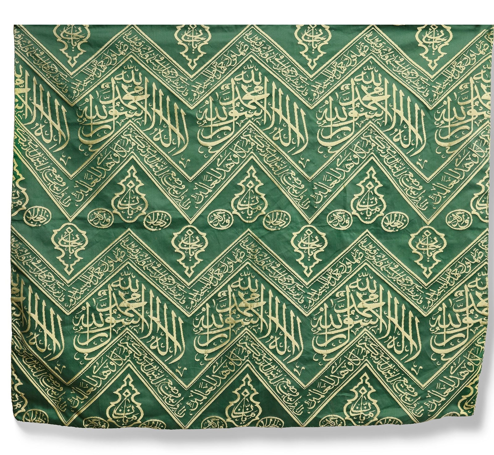AN OTTOMAN GREEN SILK KISWA TEXTILE FRAGMENT, TURKEY OR EGYPT, 20TH CENTURY: A refined fragment from the inner curtain (kiswa) that adorns the sacred interior walls of the Kaaba. Woven in cream-coloured silk against a rich green ground, the textile is composed of bands bearing